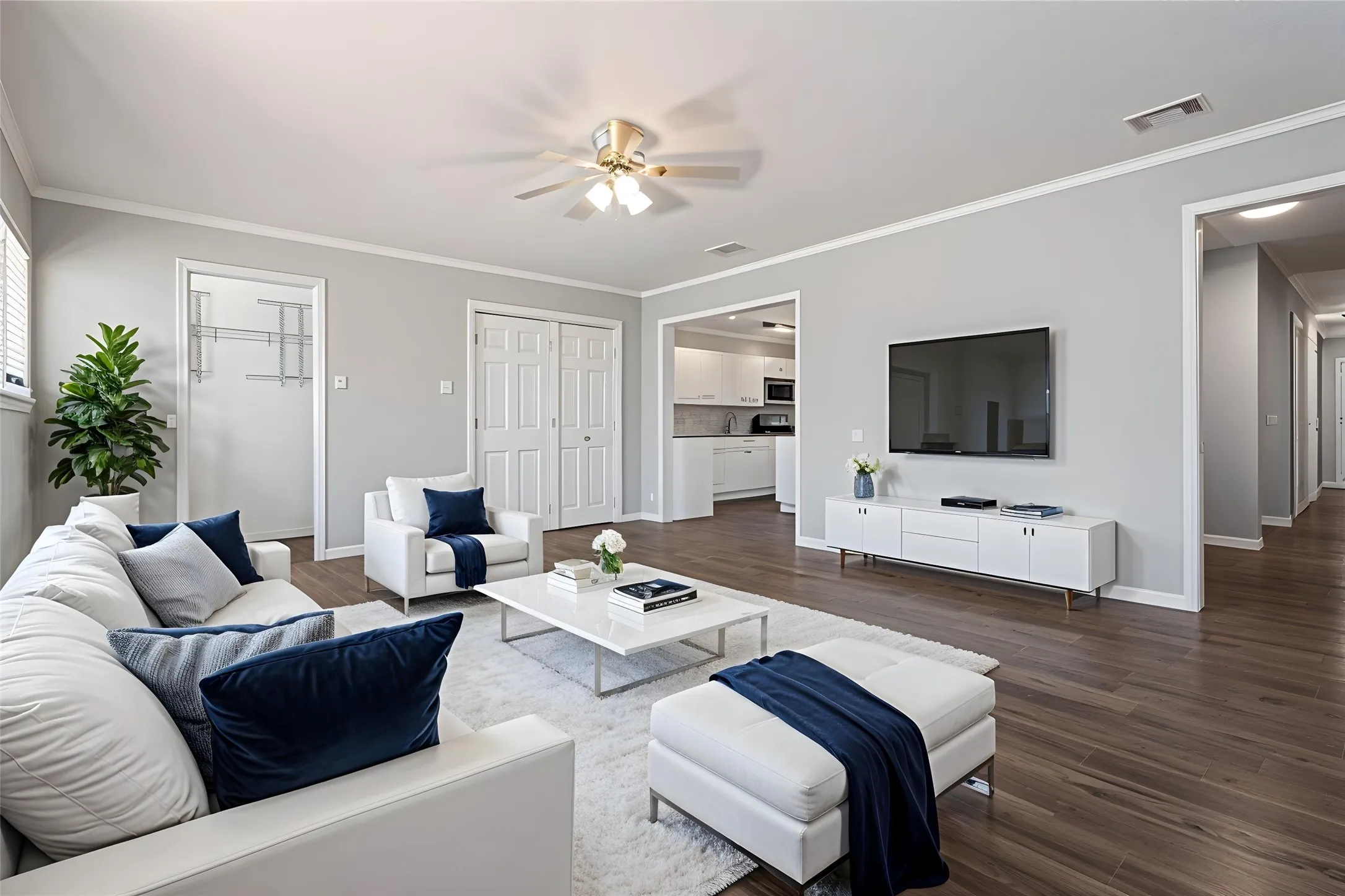 Wood-finish flooring, a ceiling fan with integrated lighting, and multiple entryways define this space