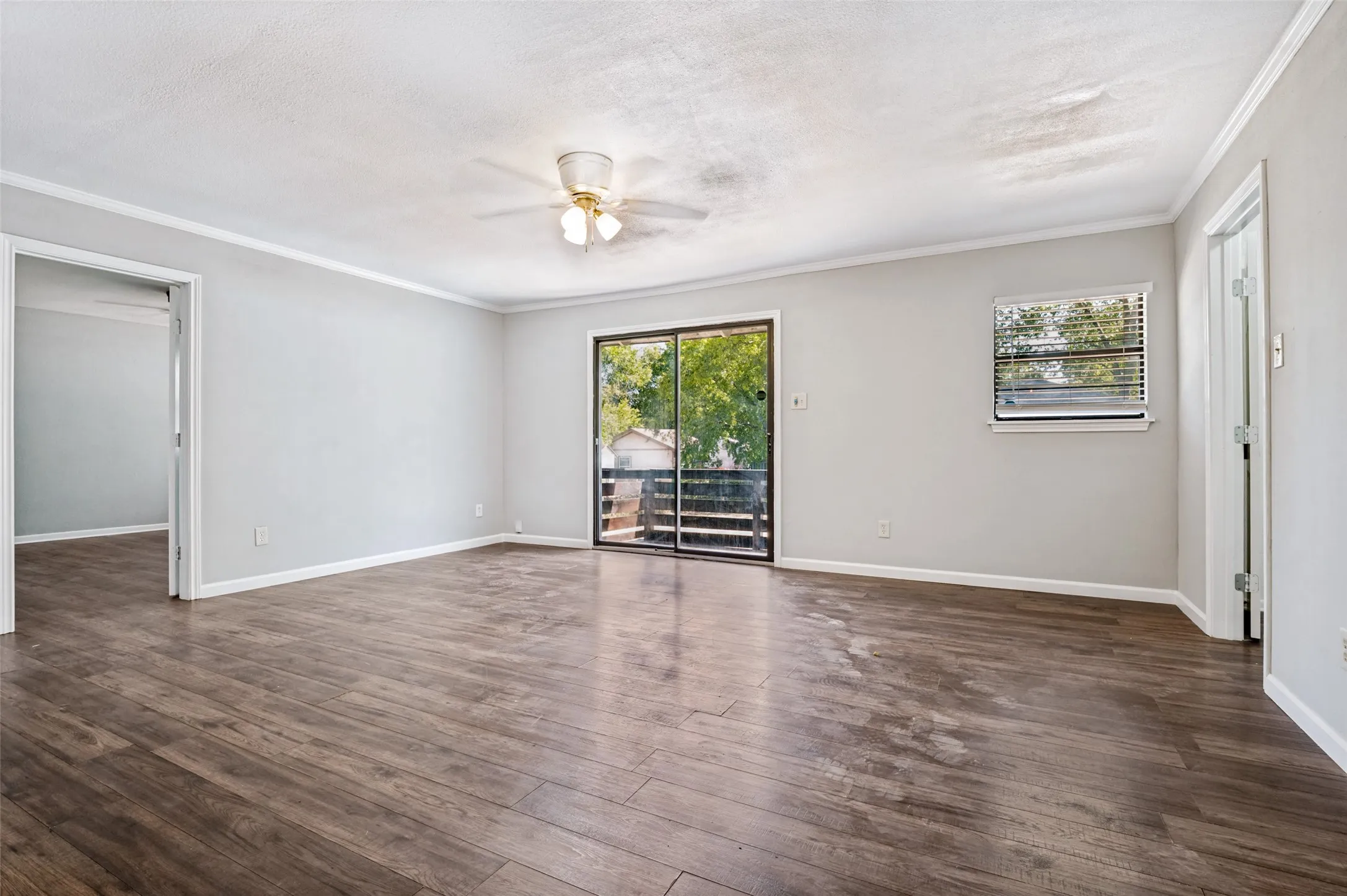 Wood-finish flooring, light gray wall paint, sliding glass door, white trim, ceiling fan