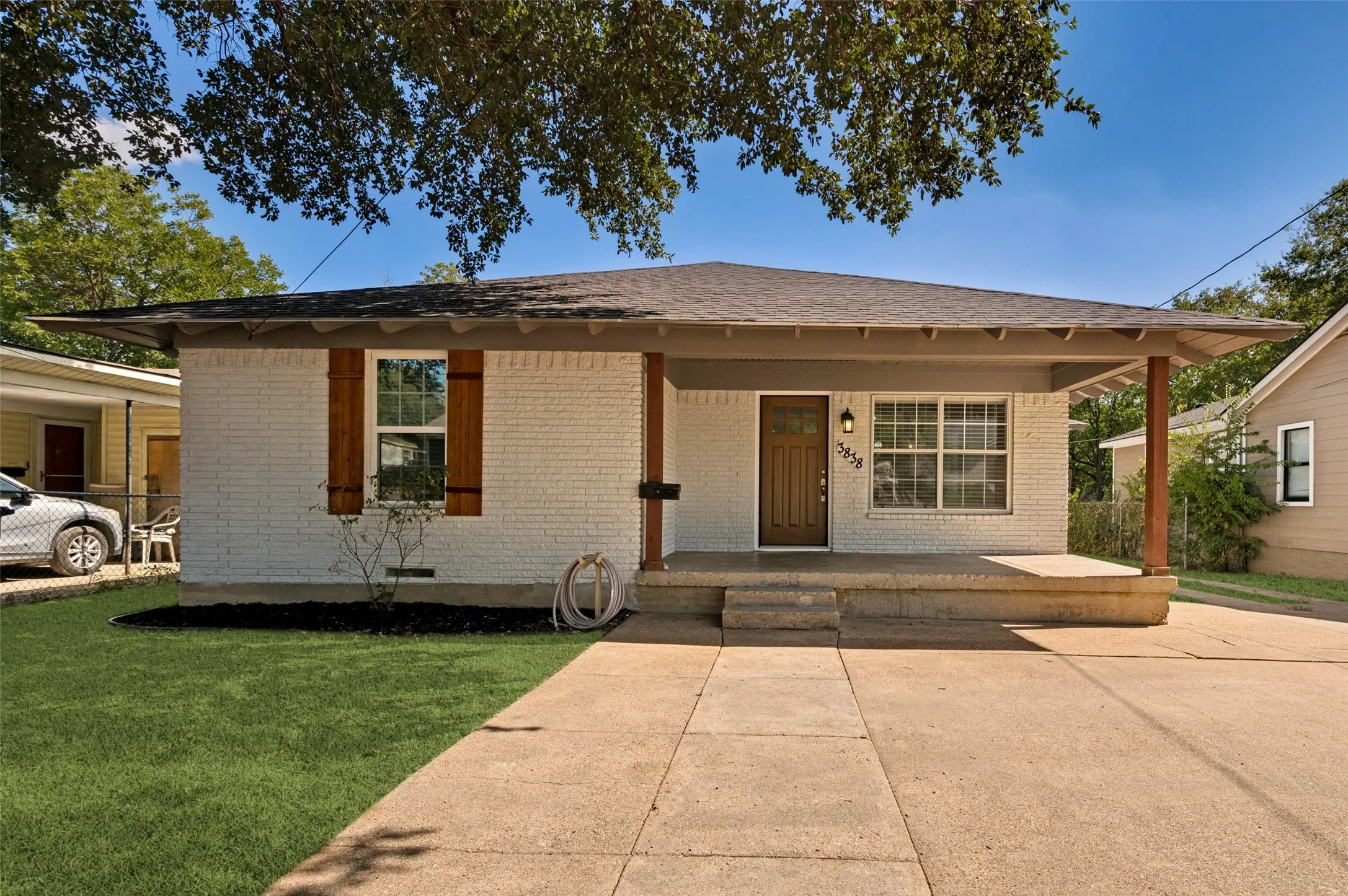White brick exterior with a covered front porch, wood entry door, and multi-pane windows