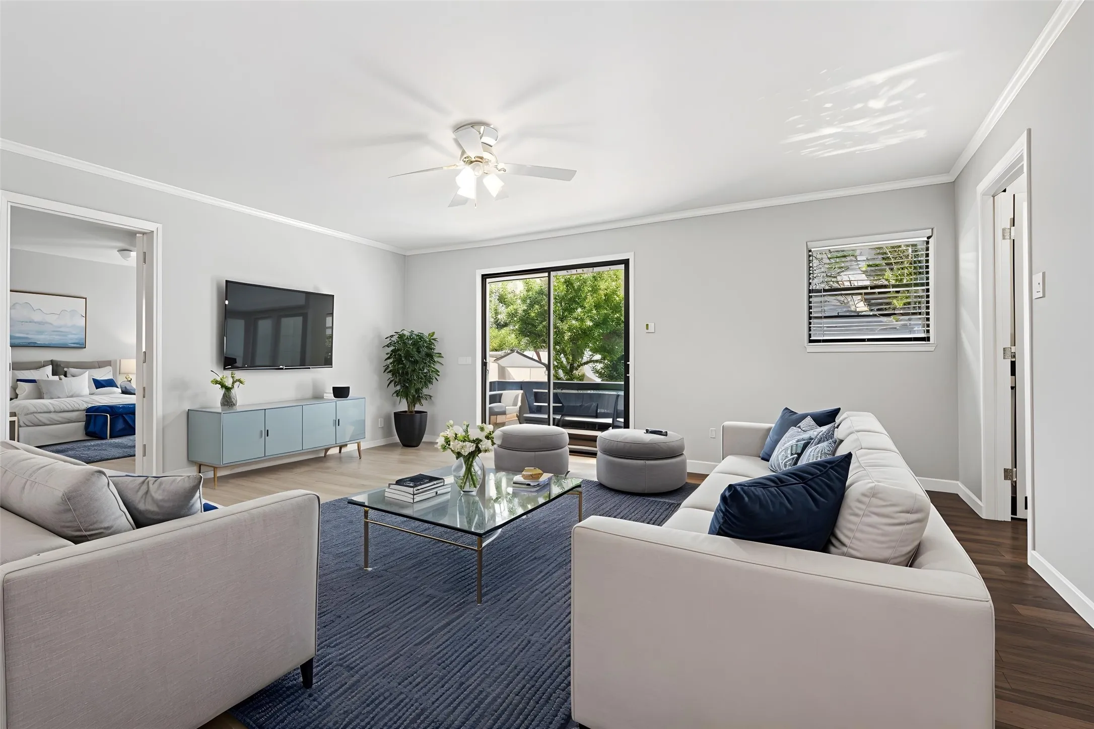 Spacious living area featuring light-colored walls, crown molding, and wood-finish flooring