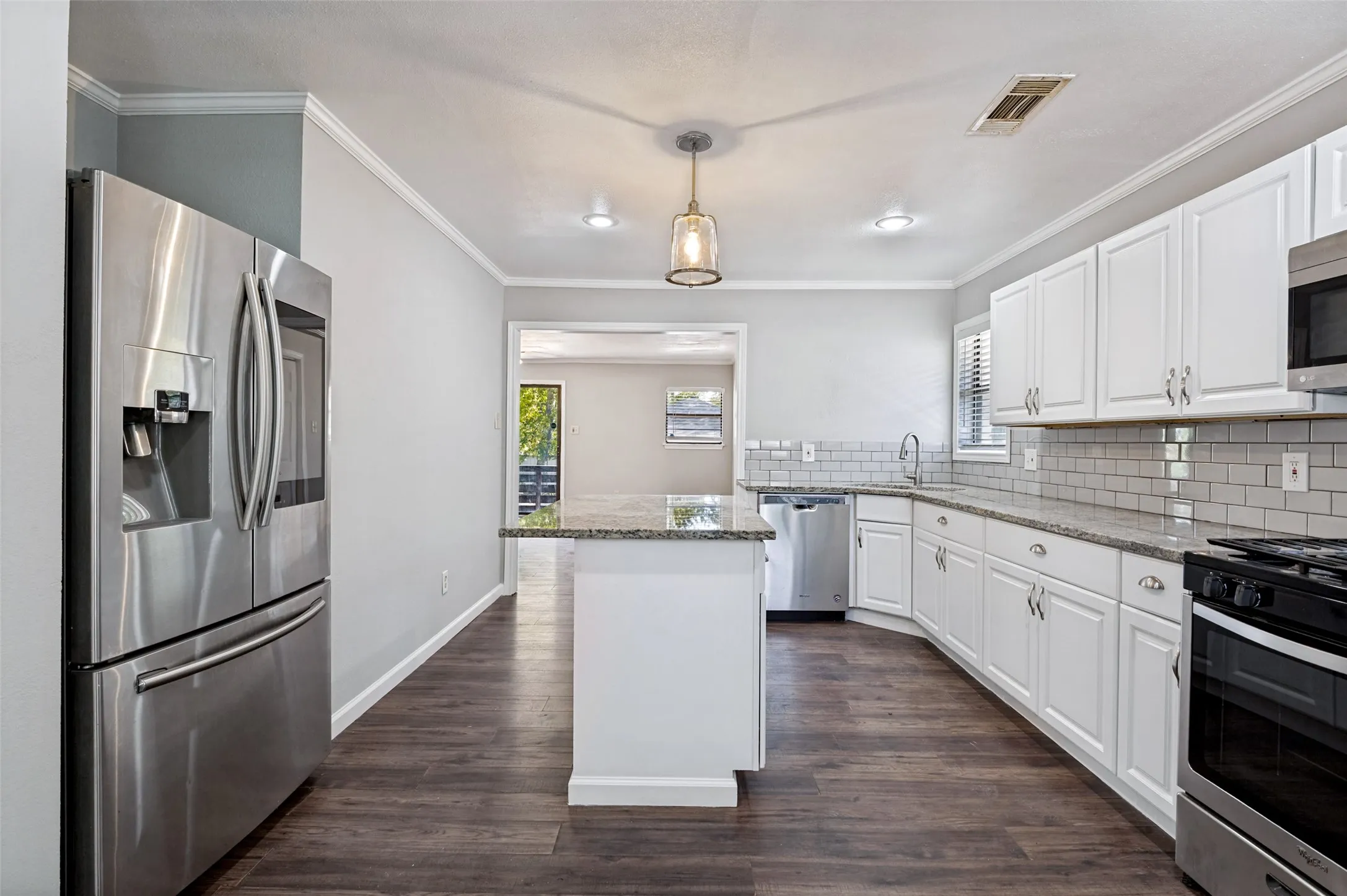 Kitchen featuring white cabinetry, granite countertops, a subway tile backsplash, and wood-finish flooring