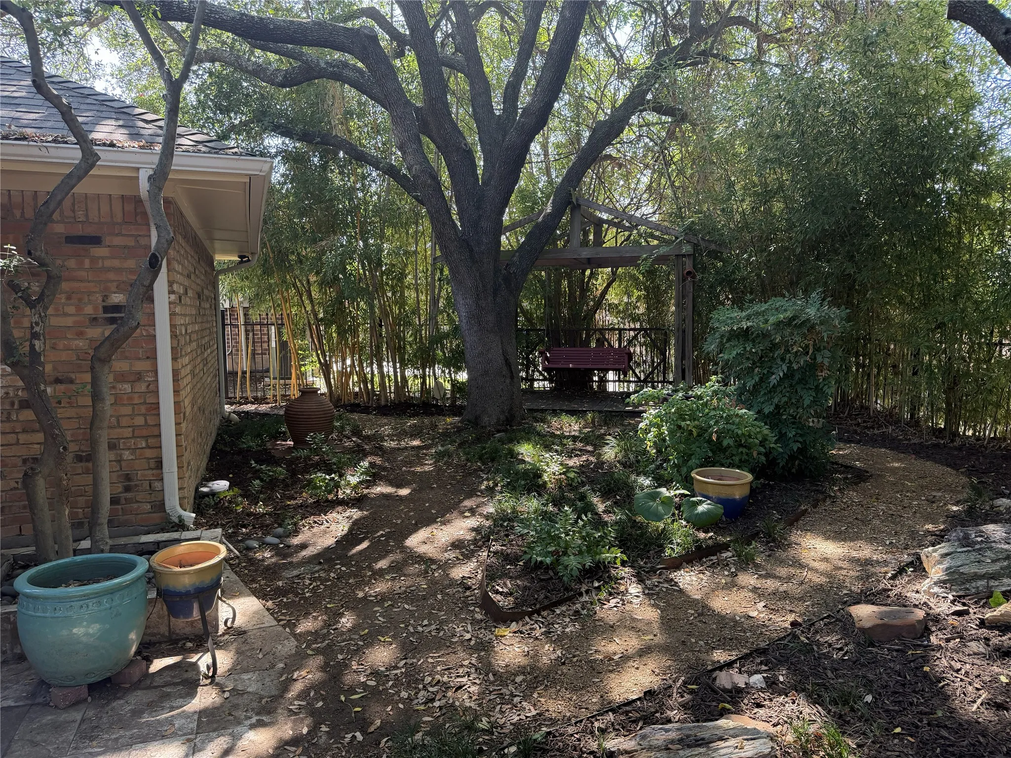 The wooden pergola offers a place to swing and enjoy the peaceful beauty of the yard.