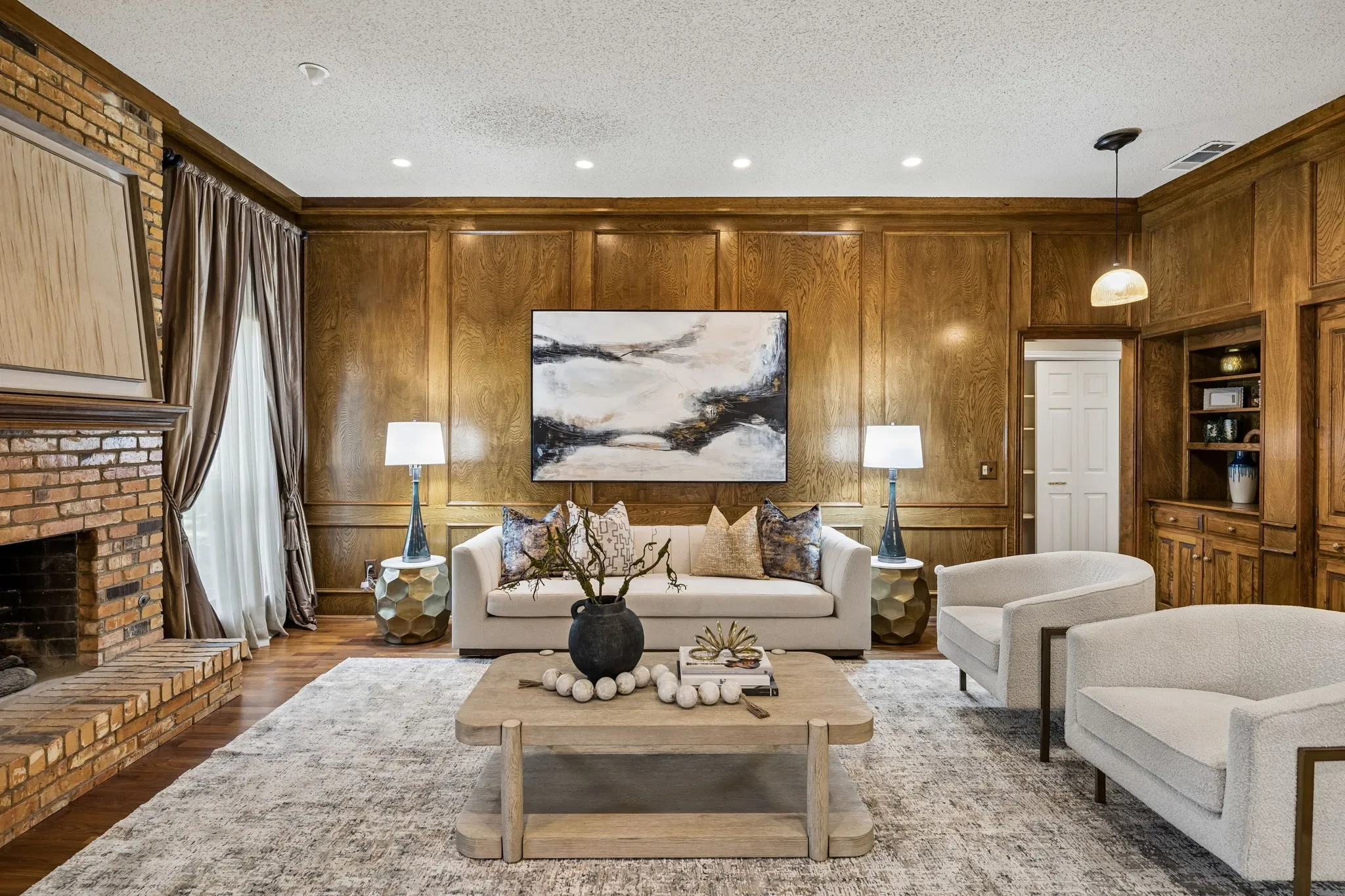 The living room has handsome paneled walls, wood floors and a fireplace with a gas starter.