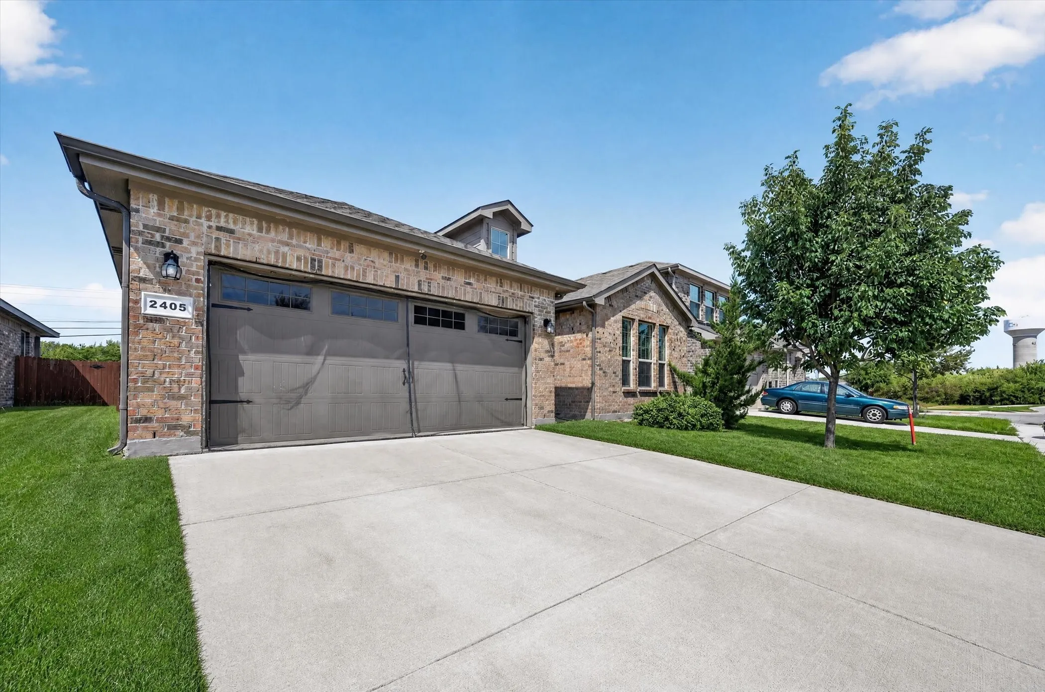 Brick and stone exterior with a concrete driveway, two-car garage, and established landscaping