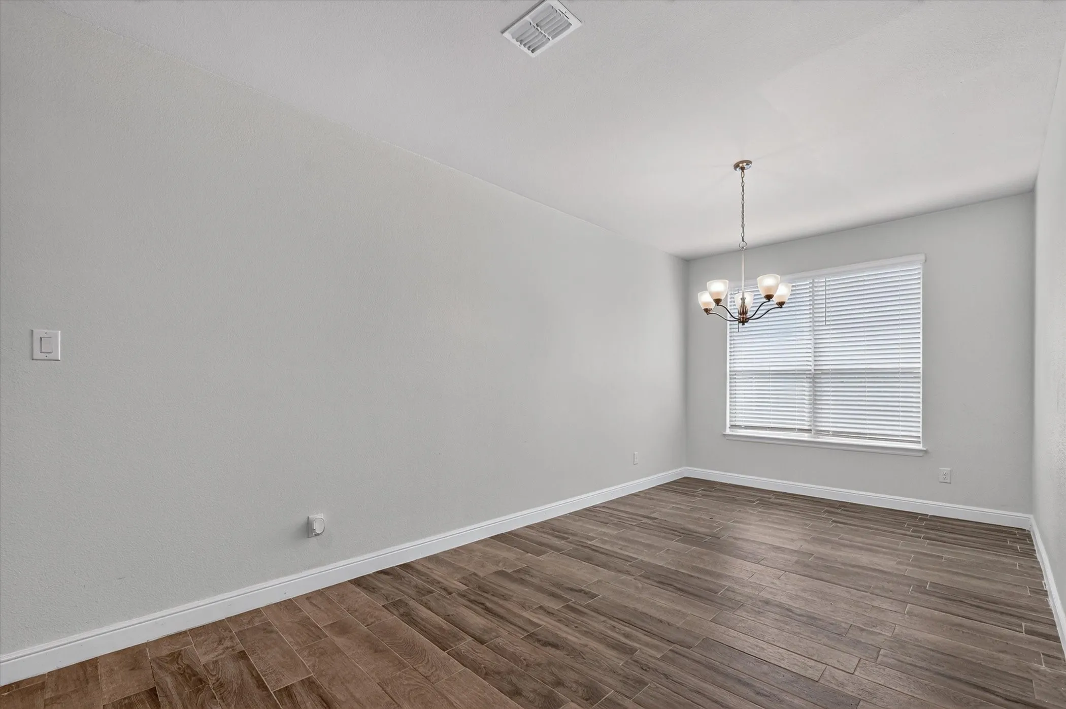 Recessed lighting, wood-finish flooring, and a multi-pane window with blinds