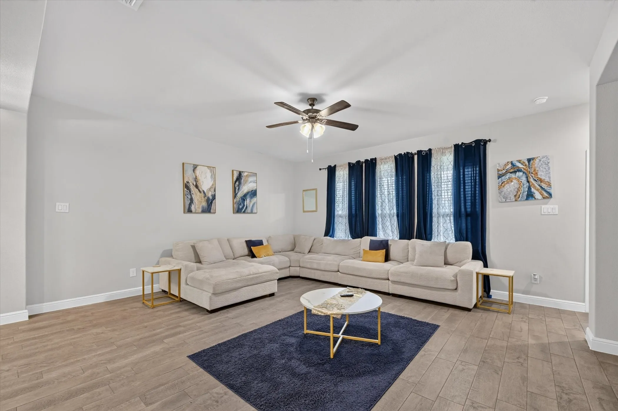 Recessed lighting, ceiling fan with integrated lighting, wood-finish flooring, and window treatments