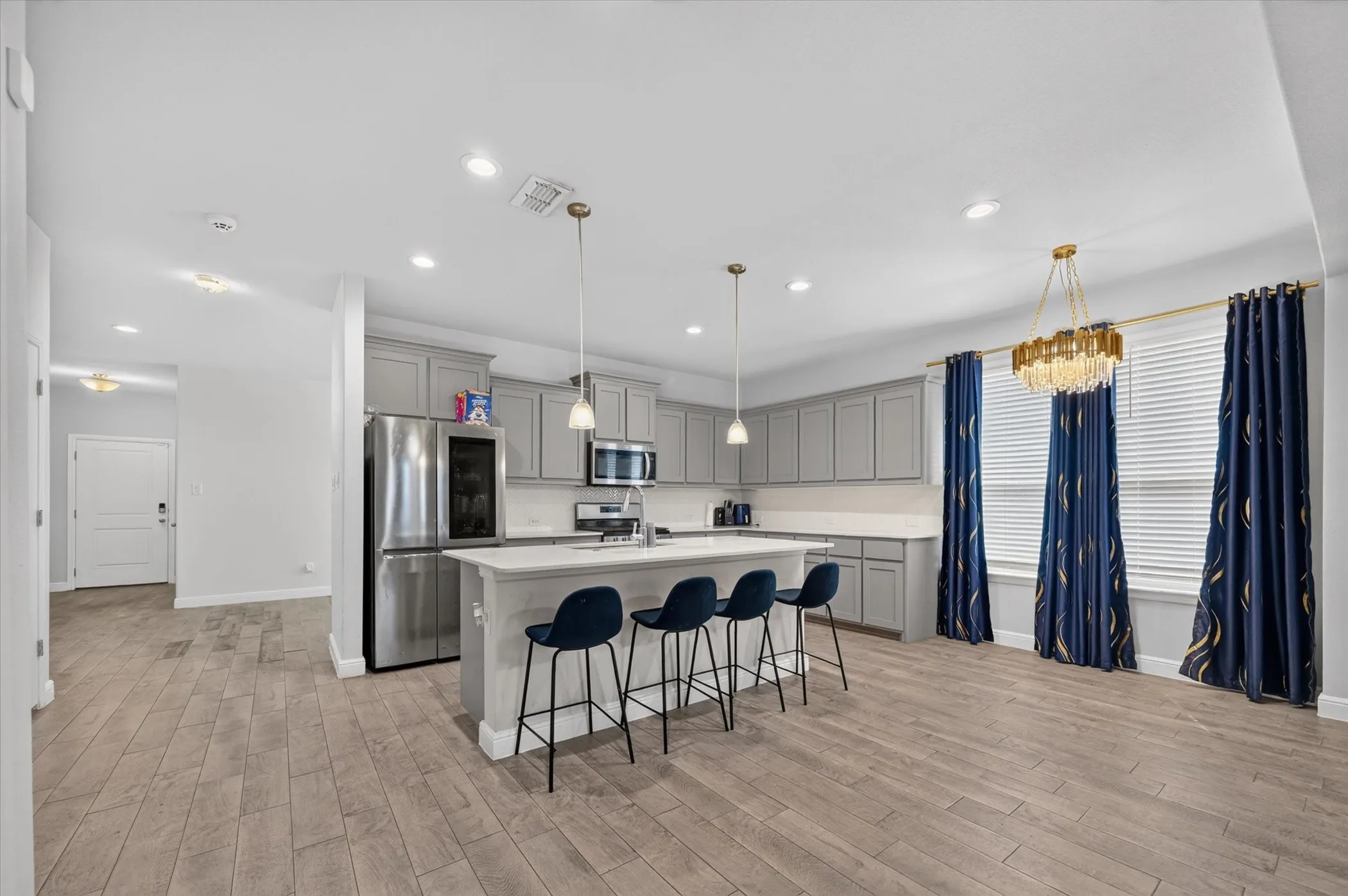 Kitchen featuring gray cabinetry, stainless steel appliances, a center island with pendant lighting, and wood-finish flooring