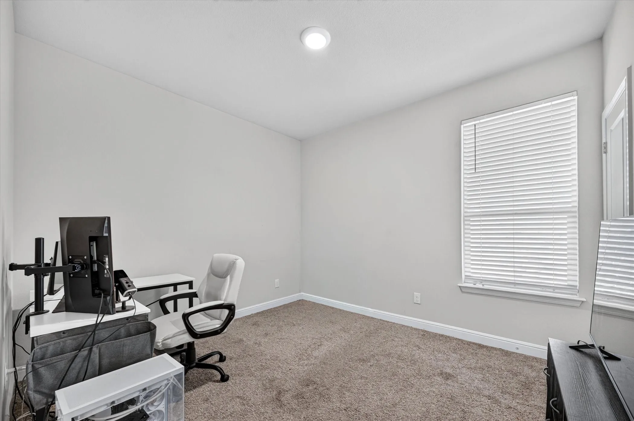 Recessed ceiling light, neutral wall paint, single window with blinds, carpet flooring