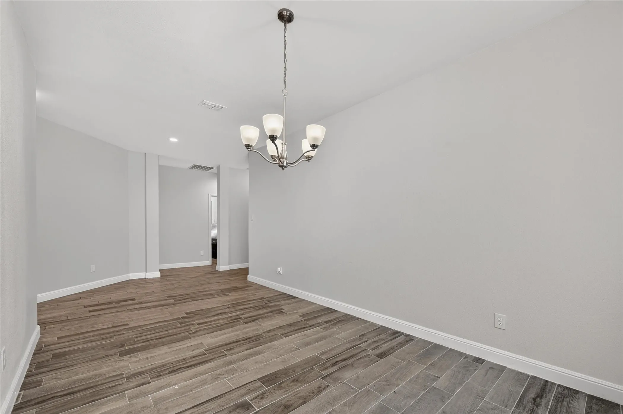 Recessed lighting, wood-finish flooring, and a contemporary chandelier