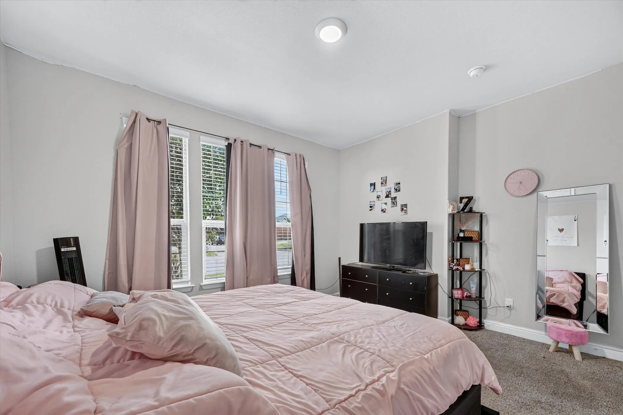 Recessed lighting illuminates the space, featuring multiple windows, neutral wall tones, and carpeted flooring