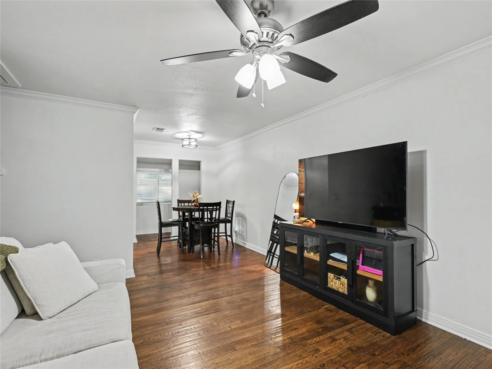 Wood-finish flooring throughout, ceiling fan with integrated lighting, recessed lighting, and crown molding