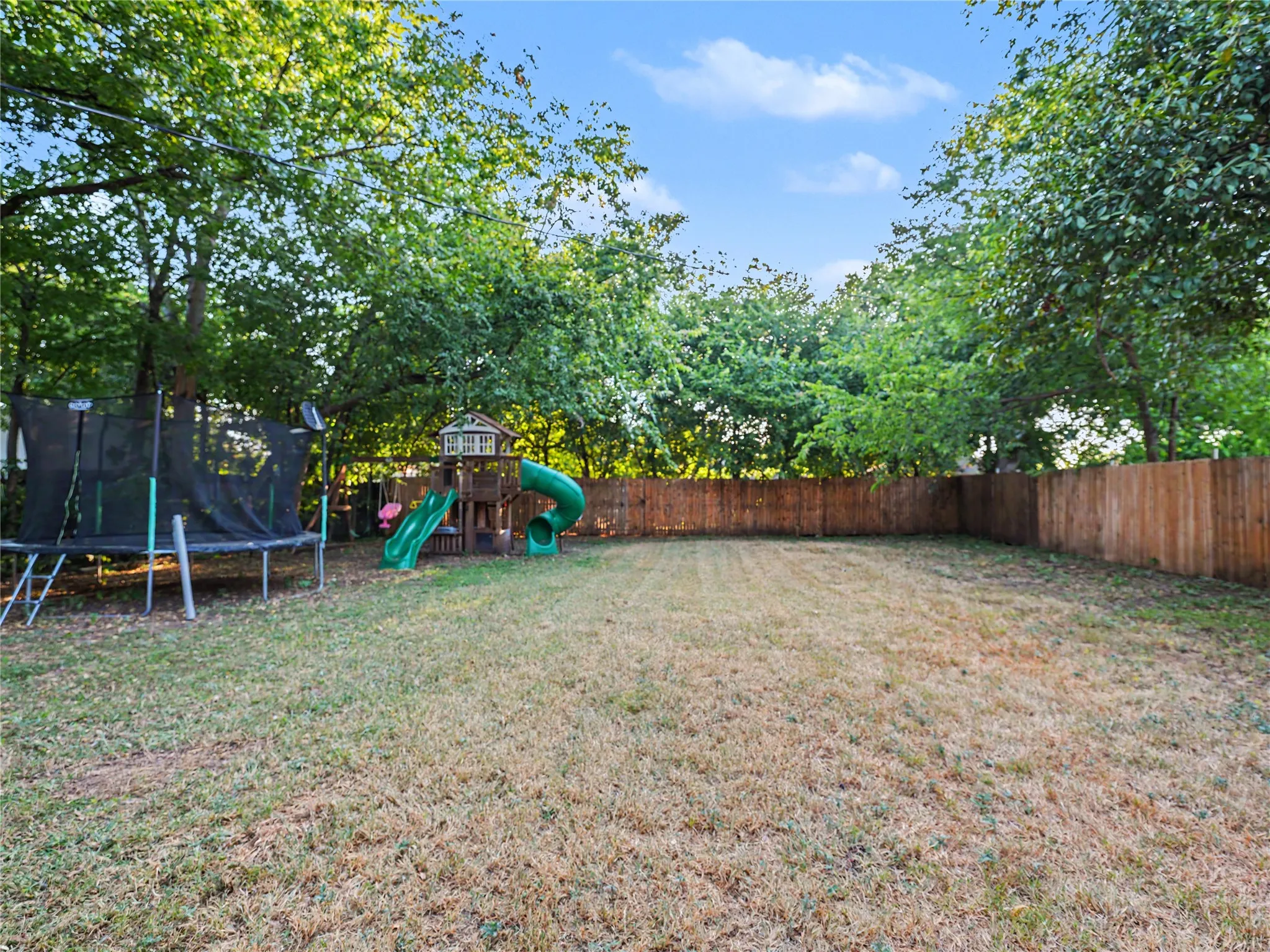 Expansive backyard with a full privacy fence and mature trees