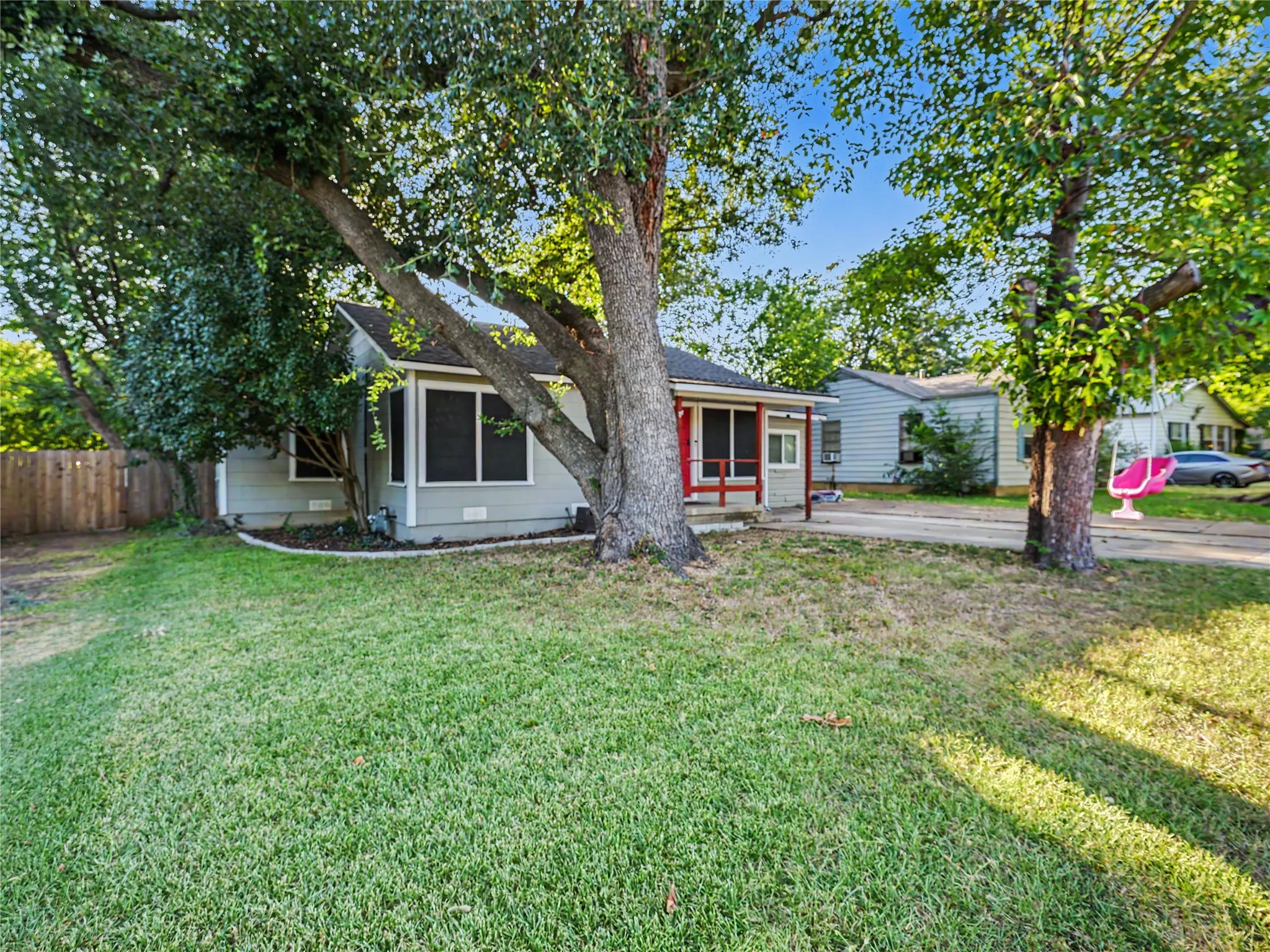 Exterior featuring a covered entry, screened porch, light-colored siding, and mature trees