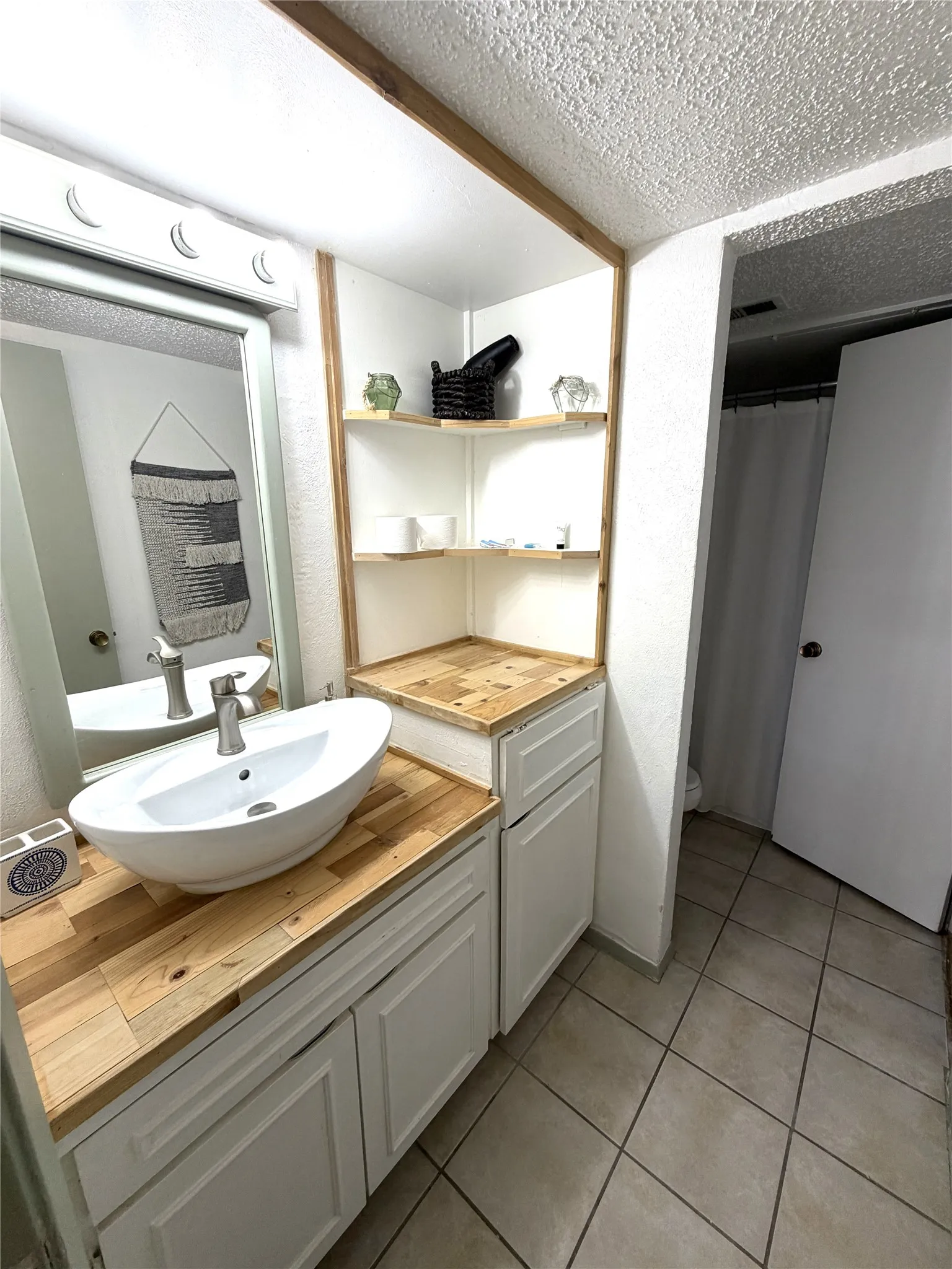 Vanity featuring a vessel sink with a wood-finish countertop