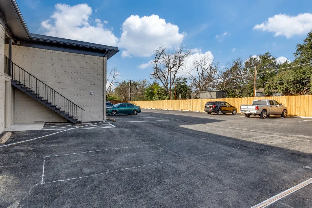 Exterior building with light-colored siding, black metal staircase, and a newly paved parking area