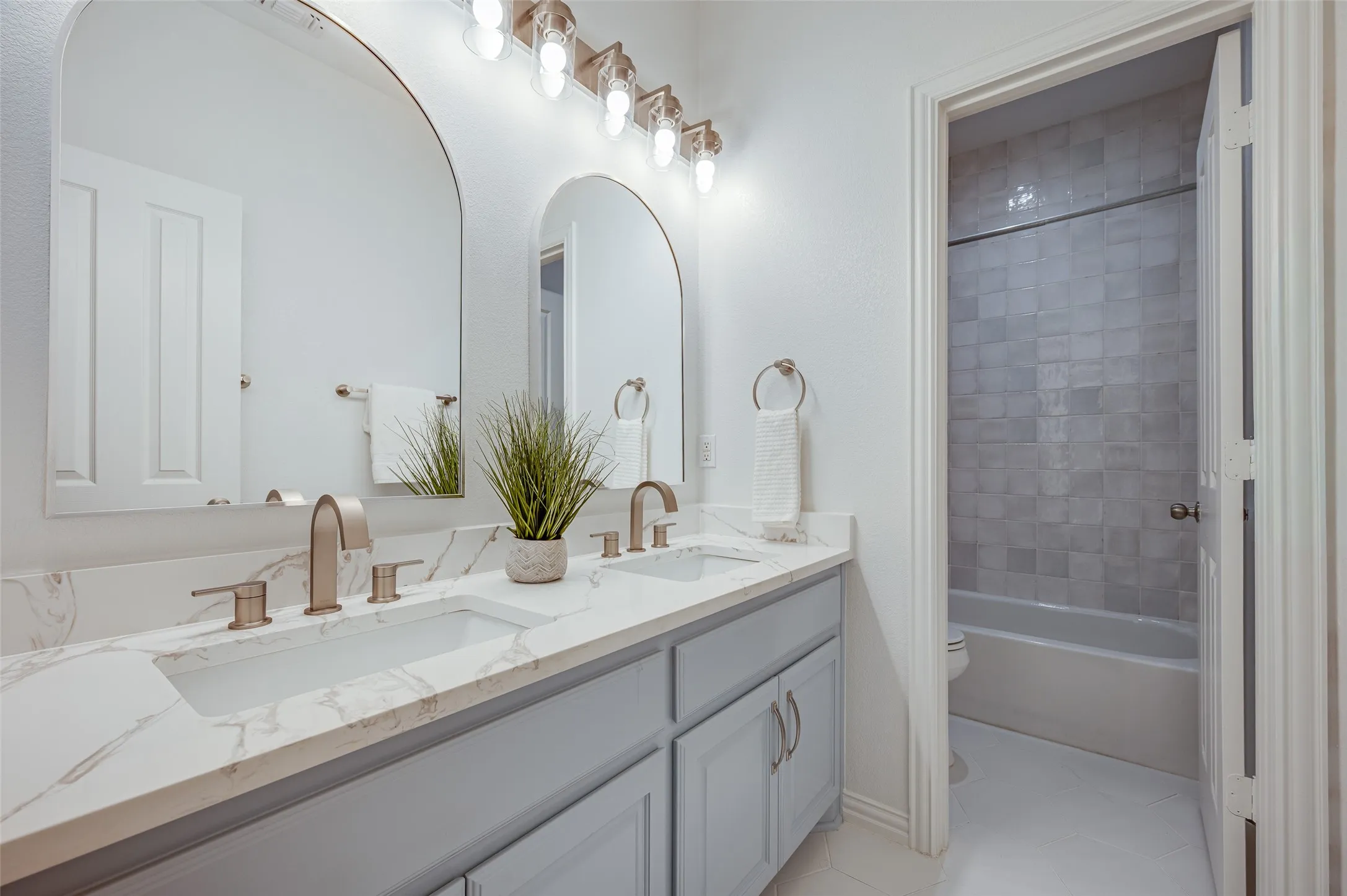 Amazing updated bathroom features a beautiful set of arched mirrors and gorgeous tile and fixtures.
