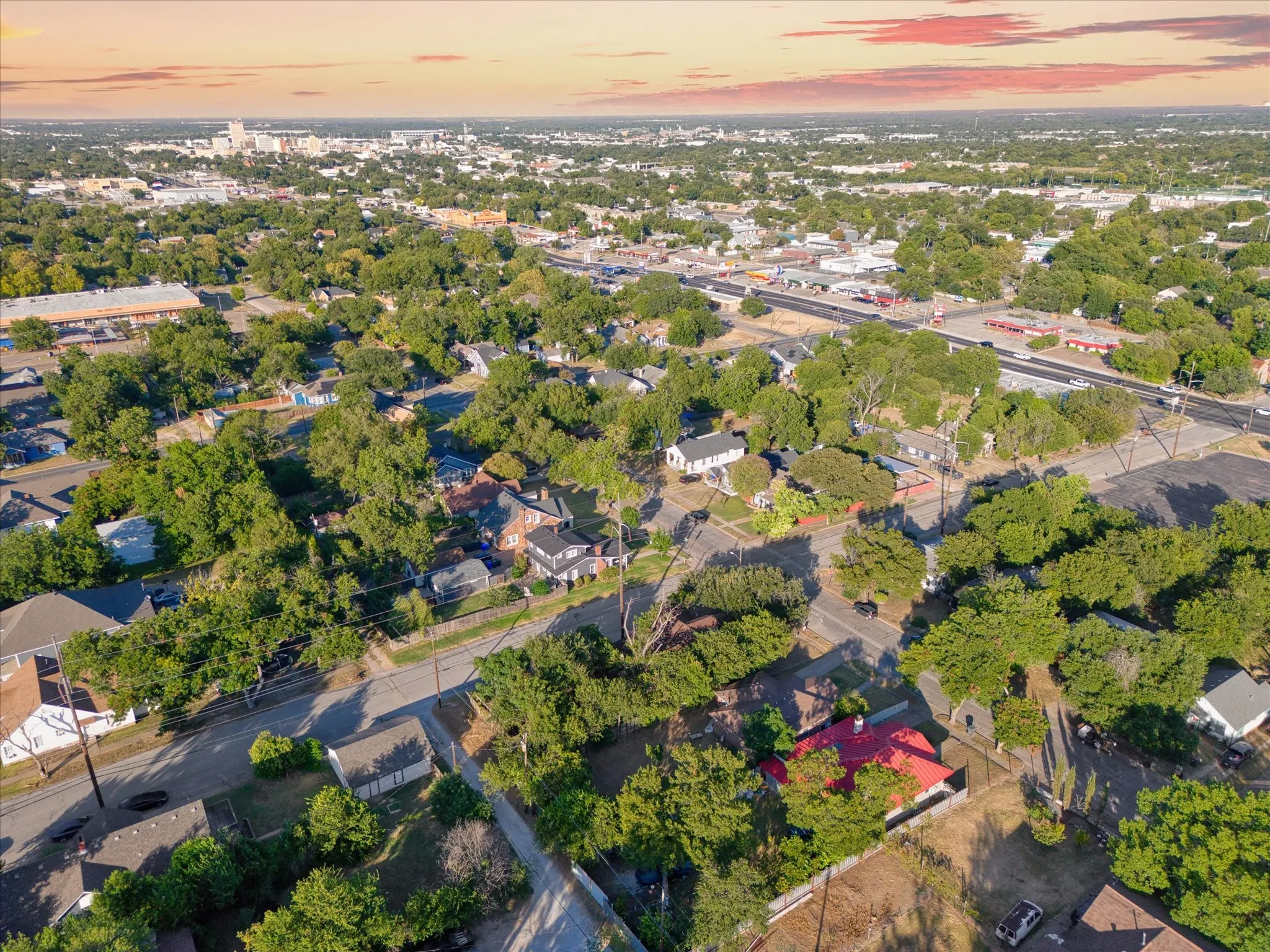 Aerial perspective of a verdant residential area featuring mature tree canopies, paved roads, and a clear skyline