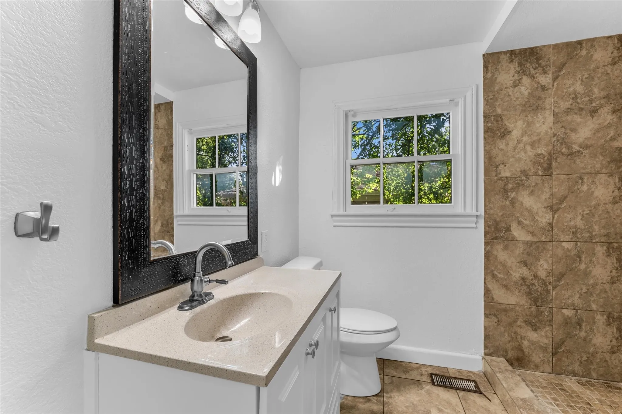 Bathroom featuring a single vanity with an integrated sink, polished chrome faucet, and a framed mirror