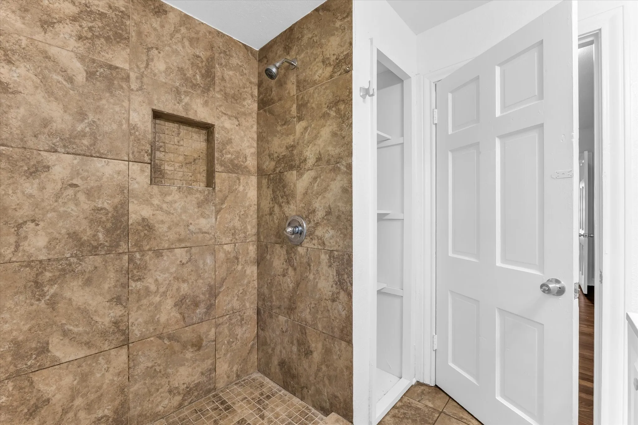 Tiled shower with a built-in niche and mosaic tile floor