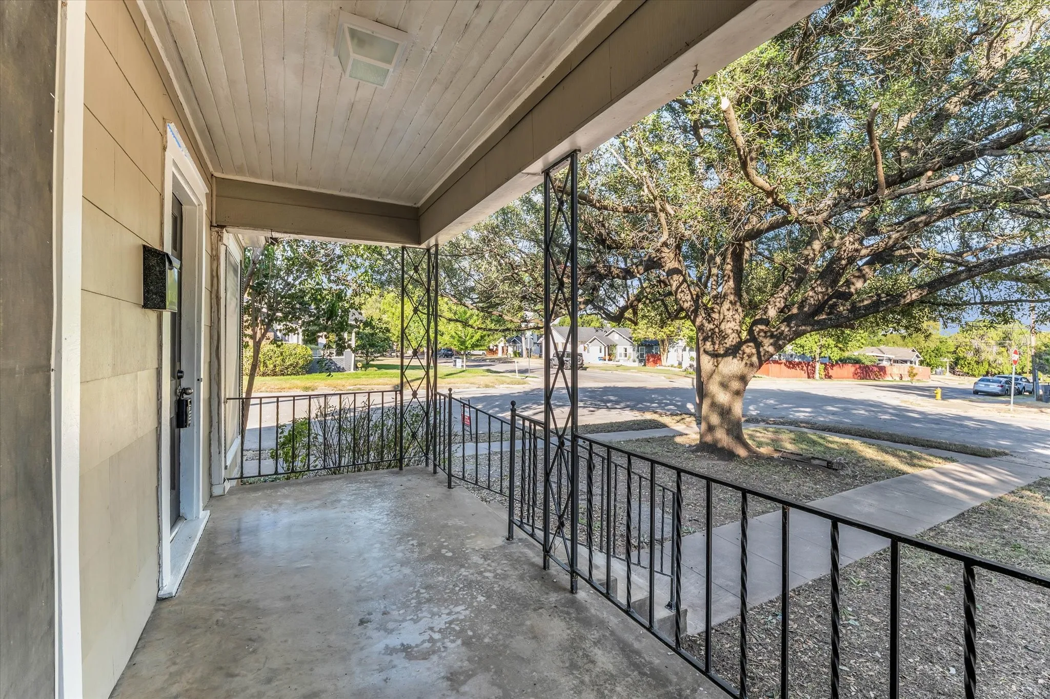 Covered porch with concrete flooring and decorative wrought iron railings