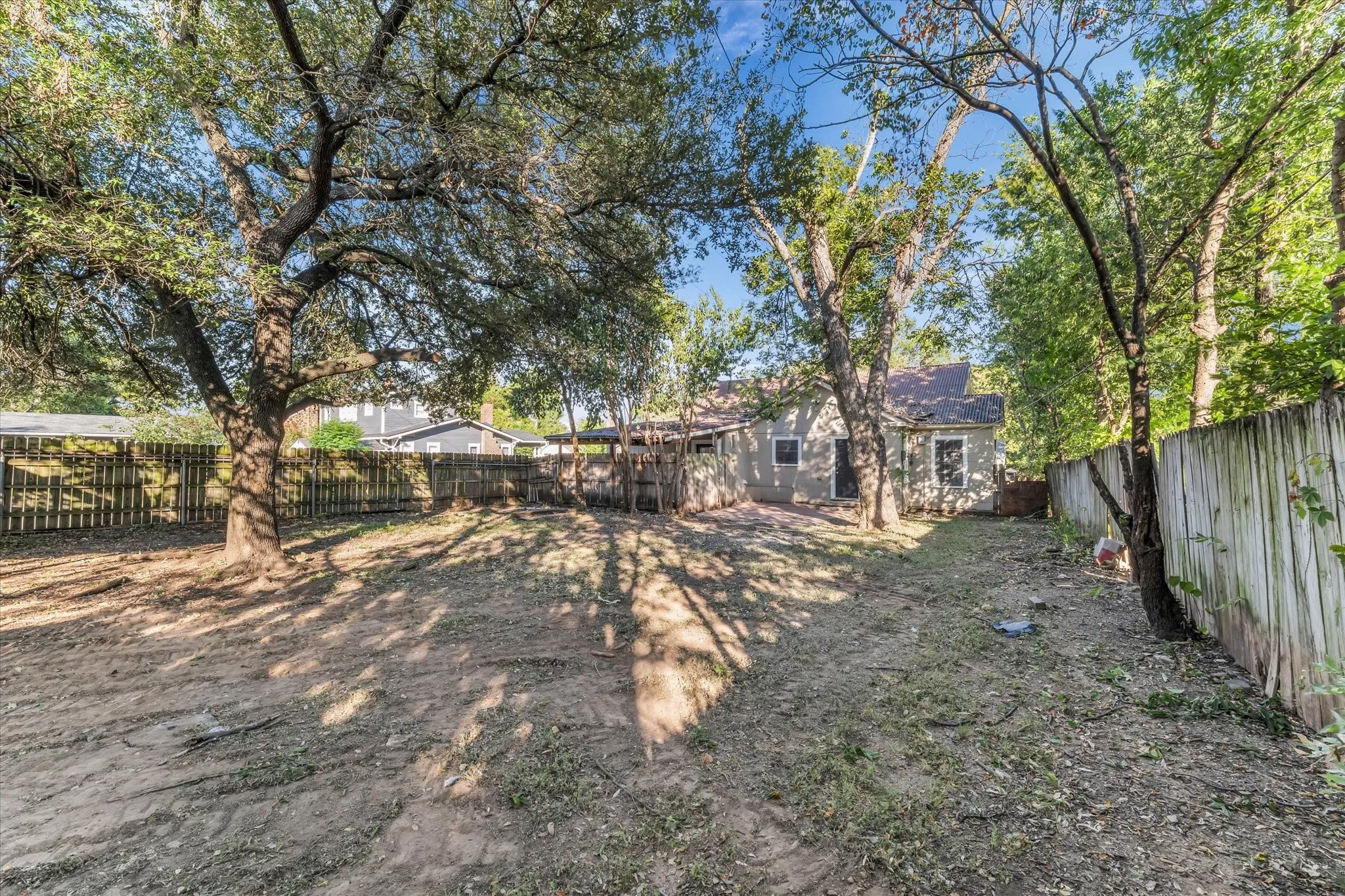 Expansive yard space with mature trees, surrounded by wood fencing