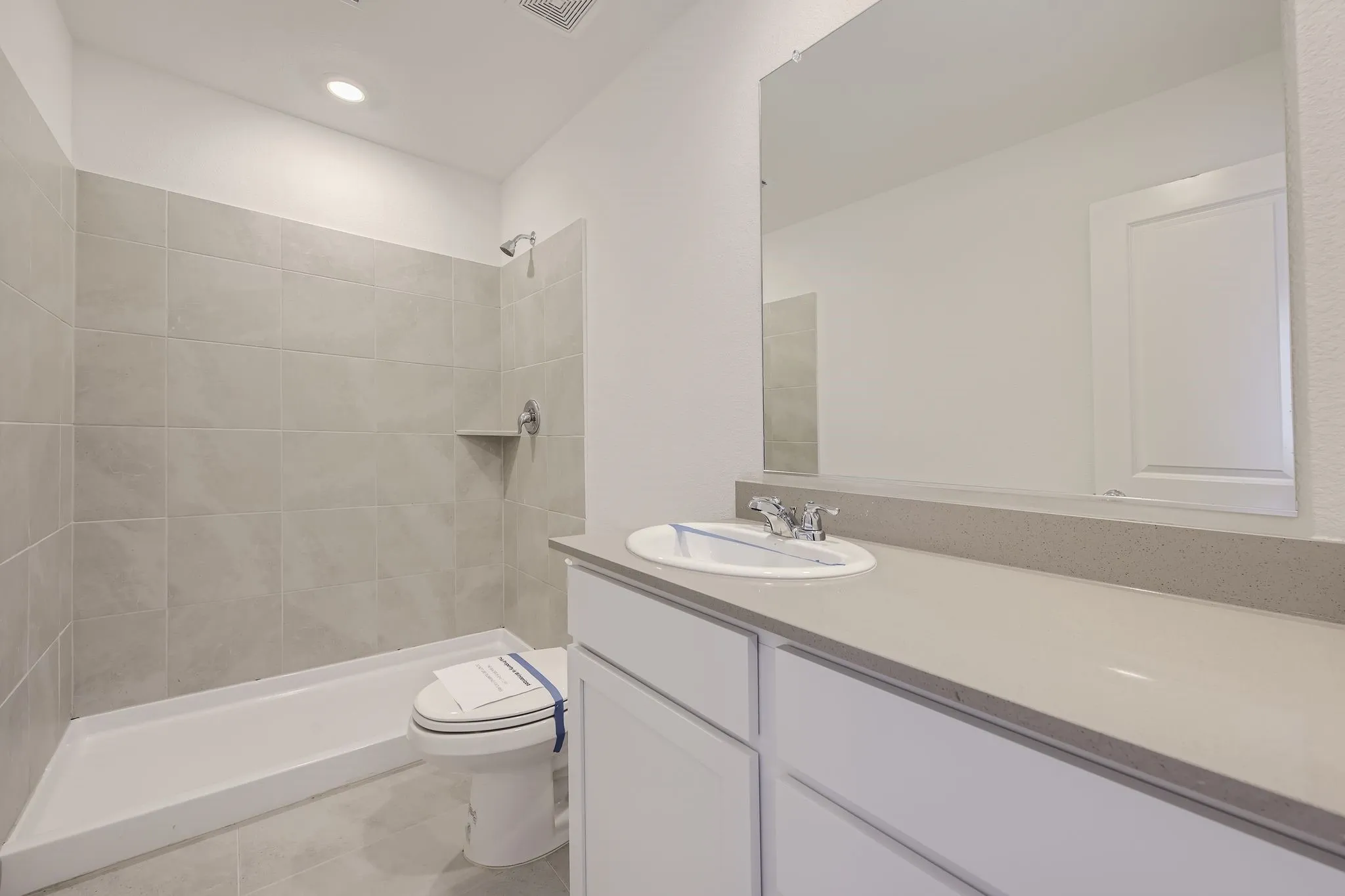 Contemporary bathroom featuring a walk-in shower with light-toned tile, a white vanity with a neutral-toned countertop, and an integrated rectangular sink