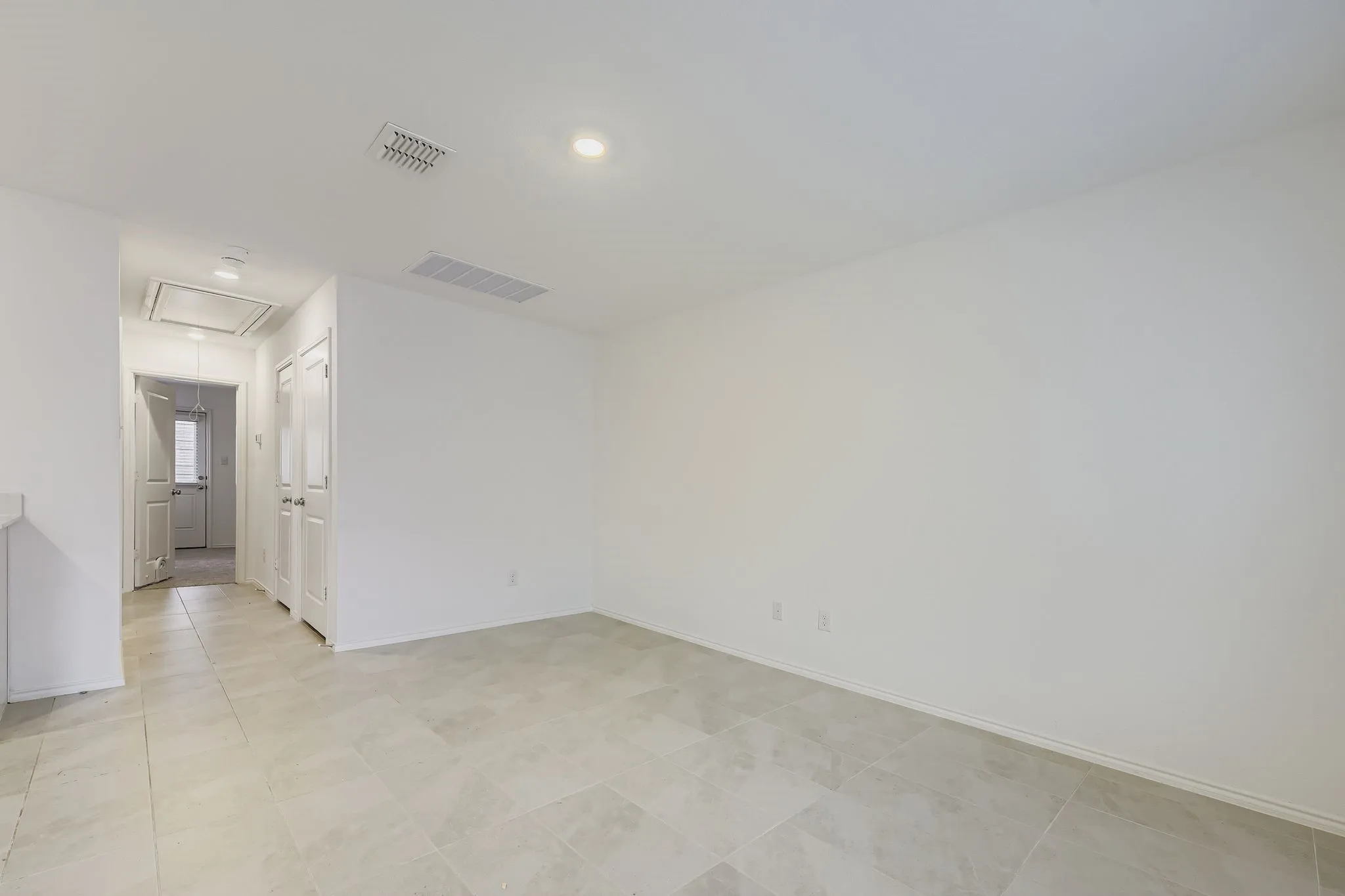 Recessed lighting, light-toned tile flooring, white walls, and a white interior door
