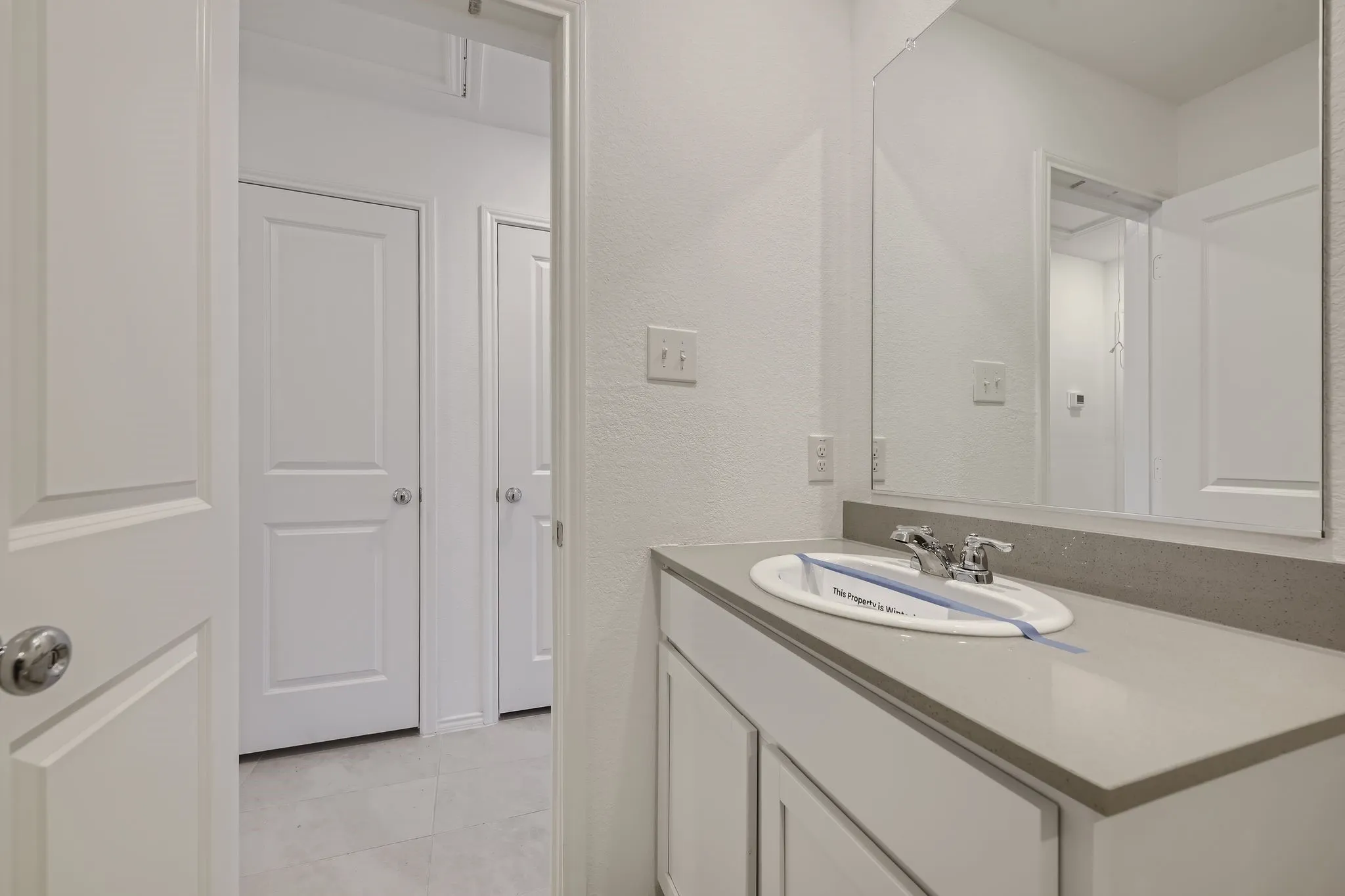 Vanity with light-toned countertop, undermount sink, and chrome faucet