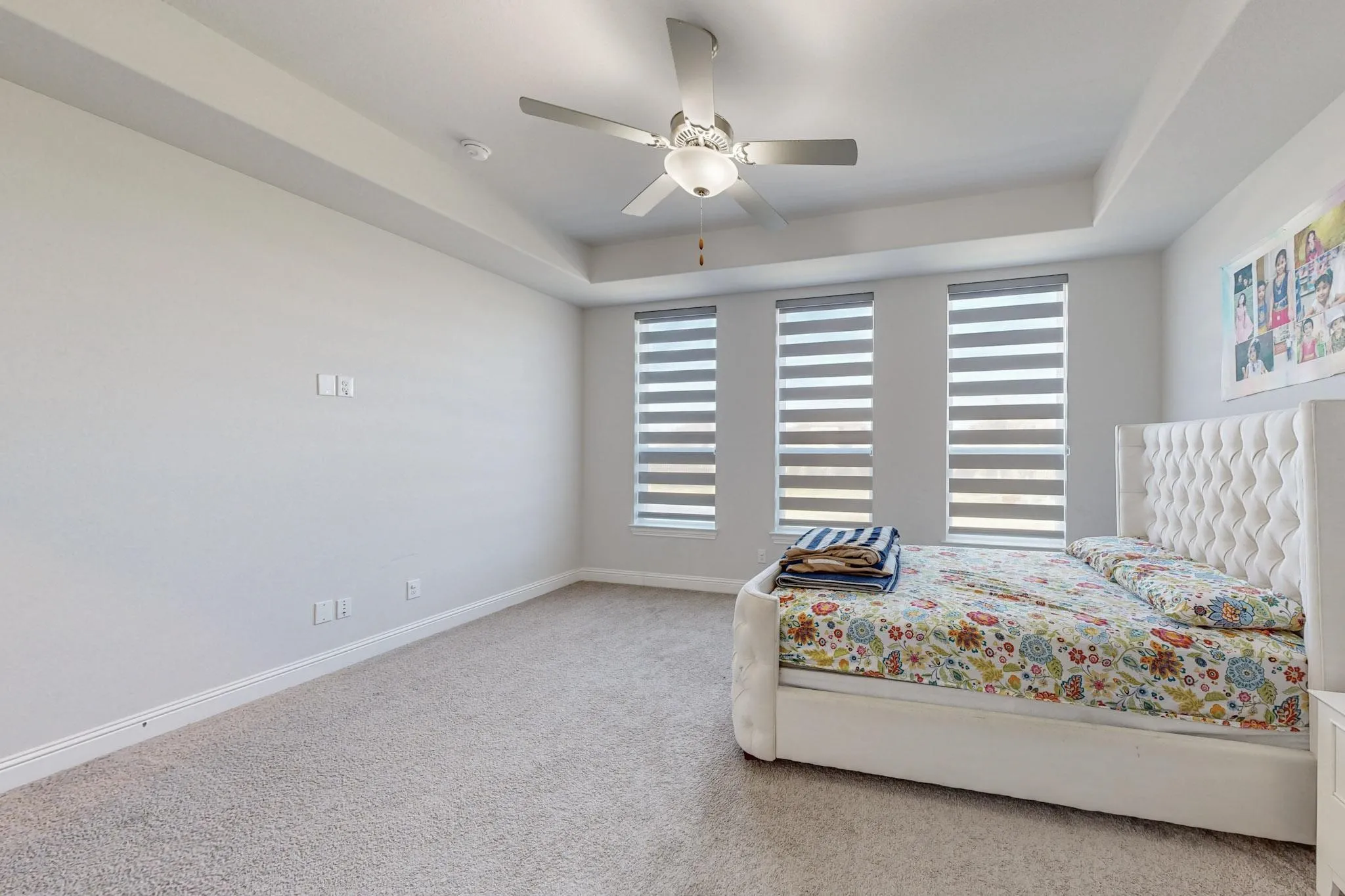 Bedroom with ceiling fan, a tray ceiling, and carpet floors