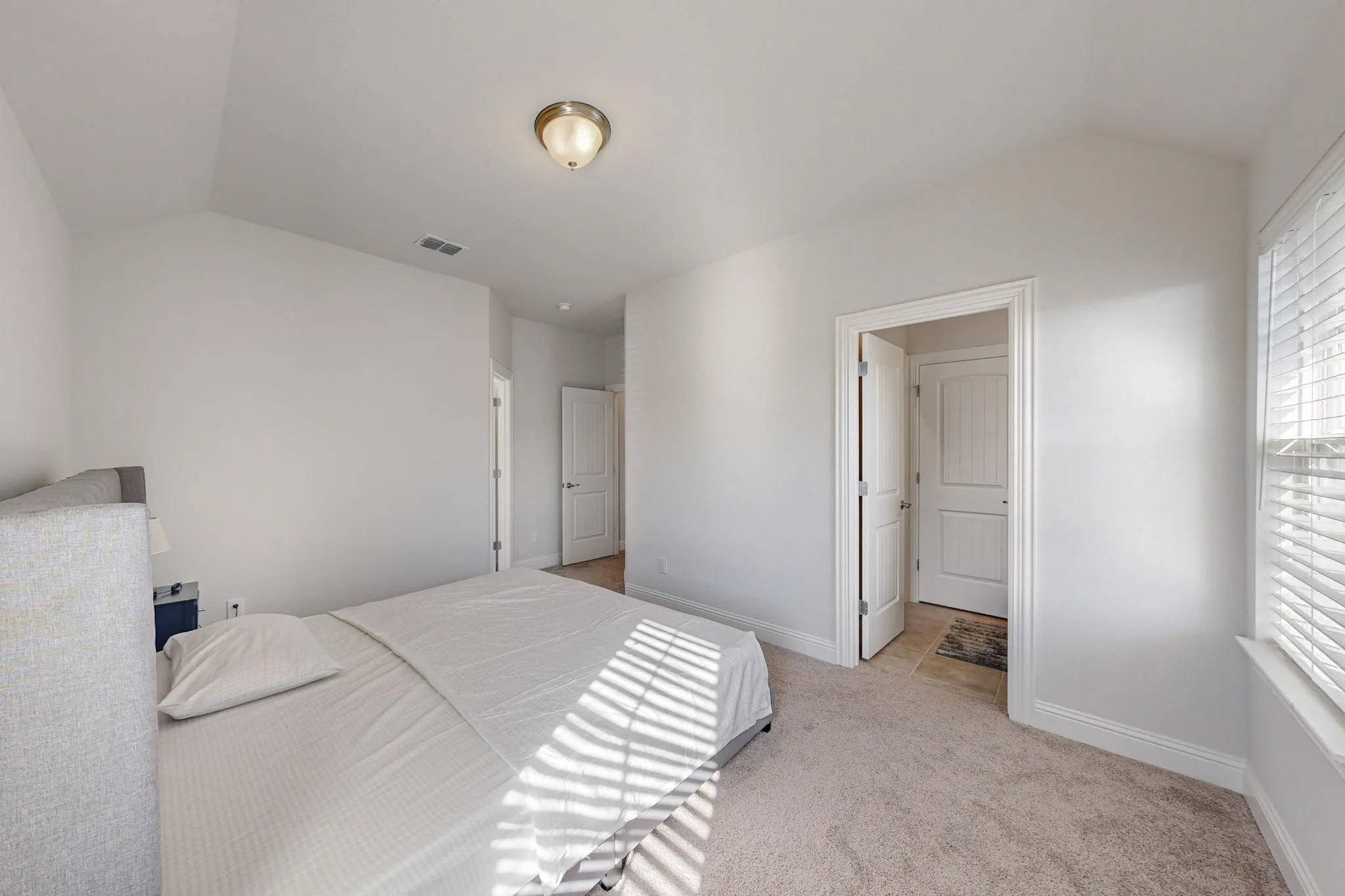 Bedroom with lofted ceiling and light carpet