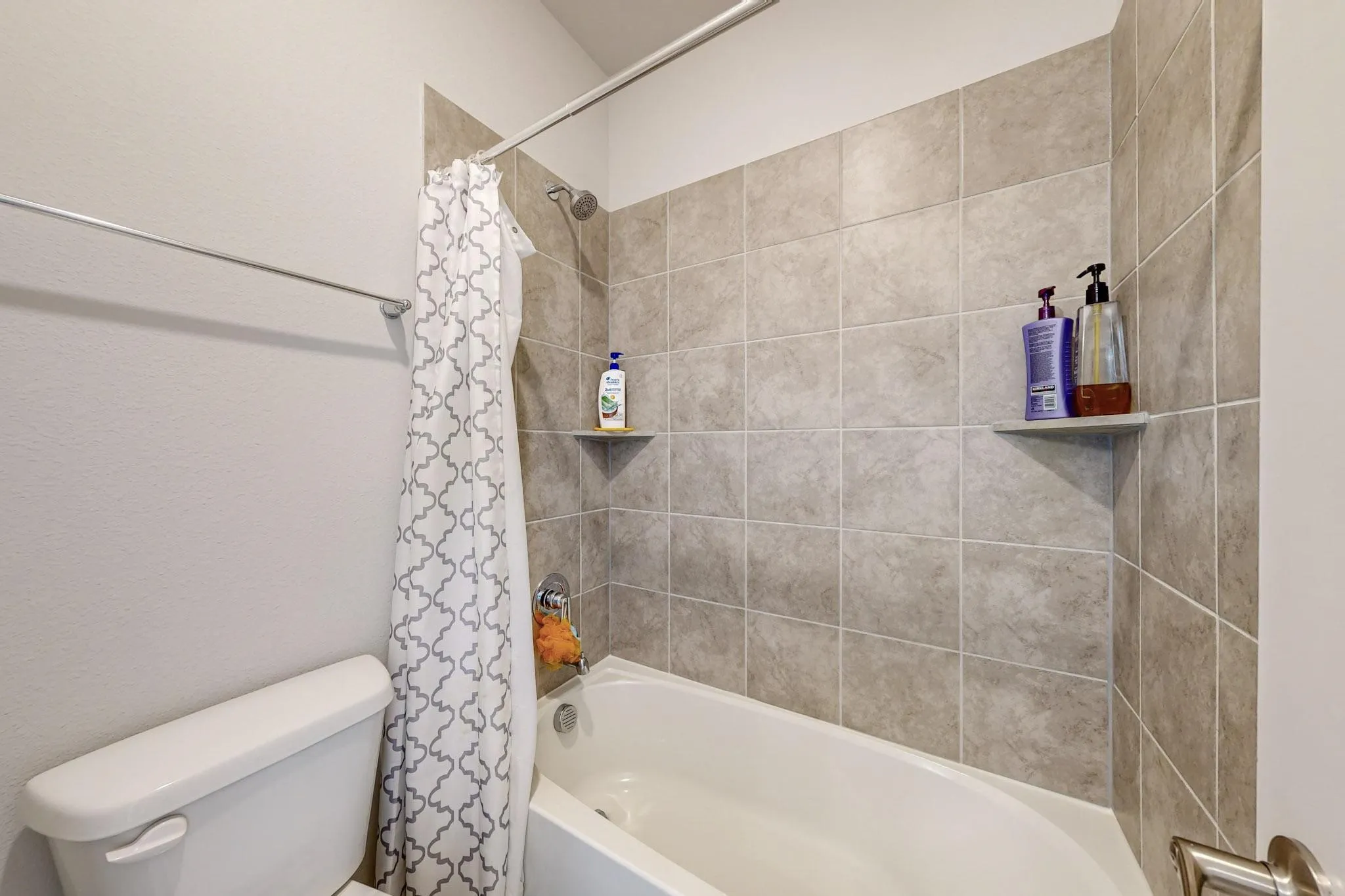 Bathroom featuring toilet and shower / bathtub combination with curtain