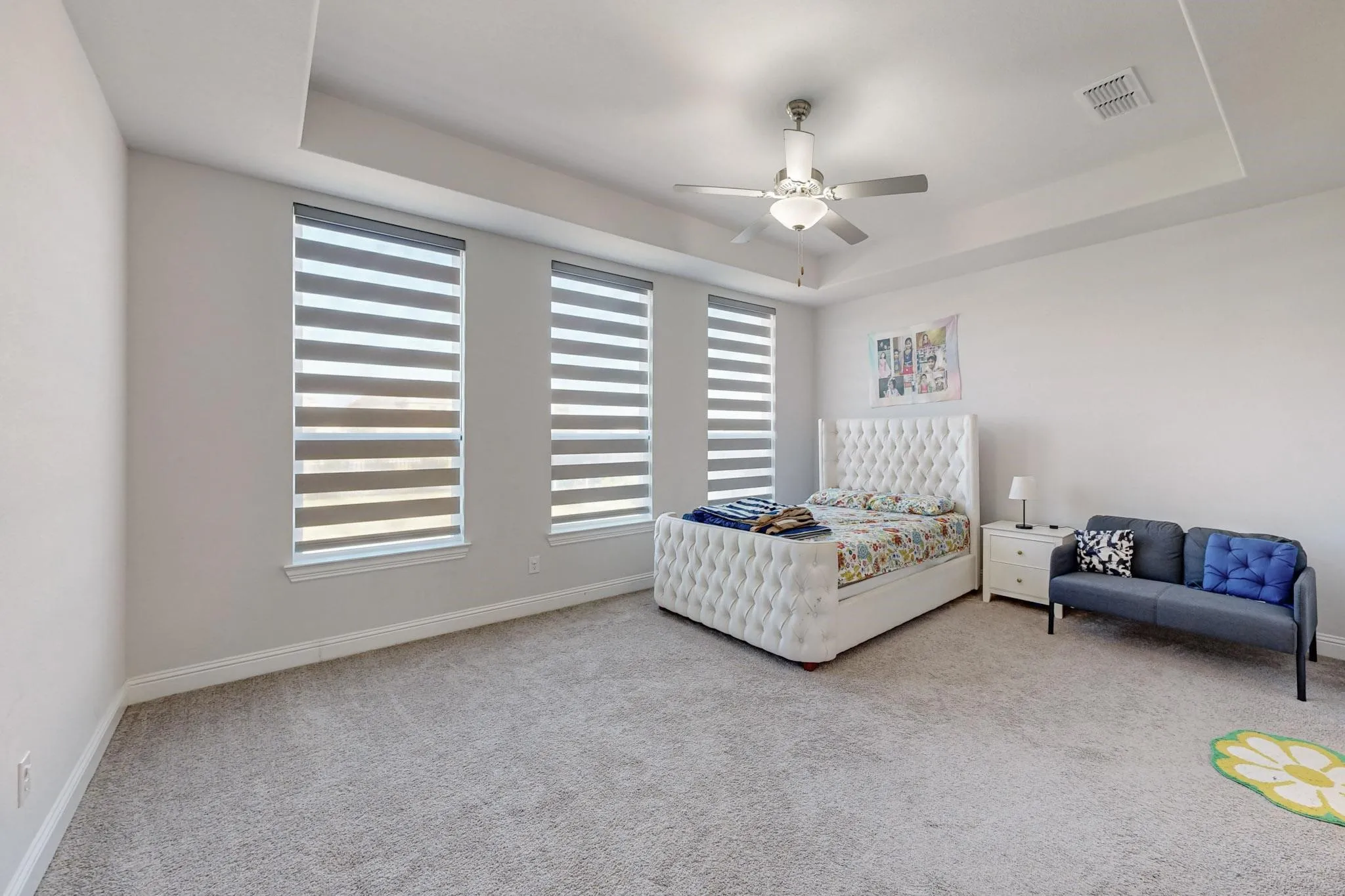 Bedroom with a raised ceiling, multiple windows, and ceiling fan