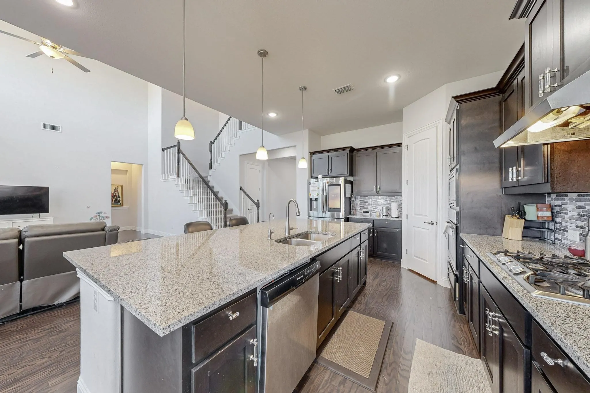 Kitchen featuring a center island with sink, dark hardwood / wood-style flooring, sink, pendant lighting, and stainless steel appliances