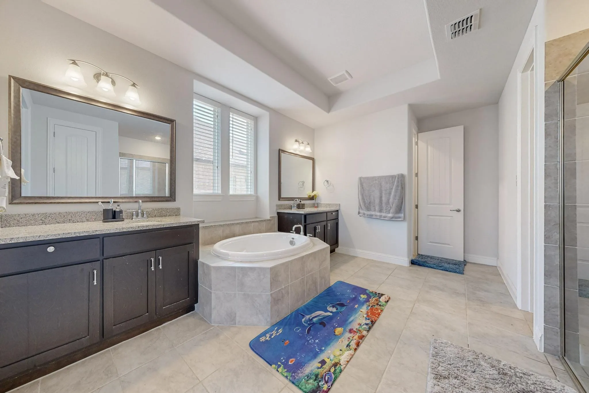 Bathroom featuring vanity, a raised ceiling, shower with separate bathtub, and tile patterned flooring