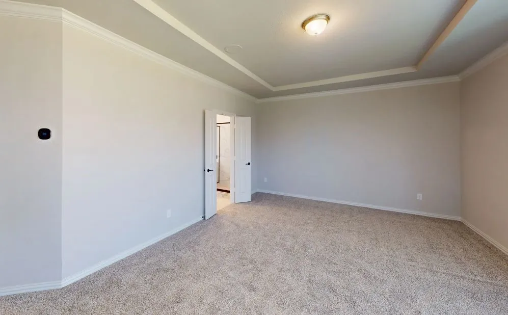 Spacious room featuring tray ceiling, crown molding, and neutral carpet flooring