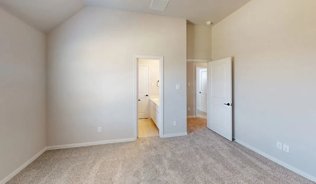 Vaulted ceiling with neutral painted walls and carpeted flooring