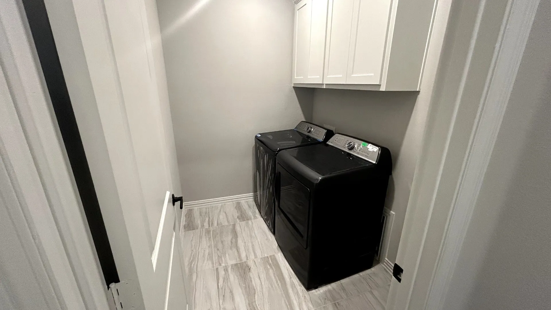 White shaker-style cabinetry, light gray wall color, and wood-finish tile flooring