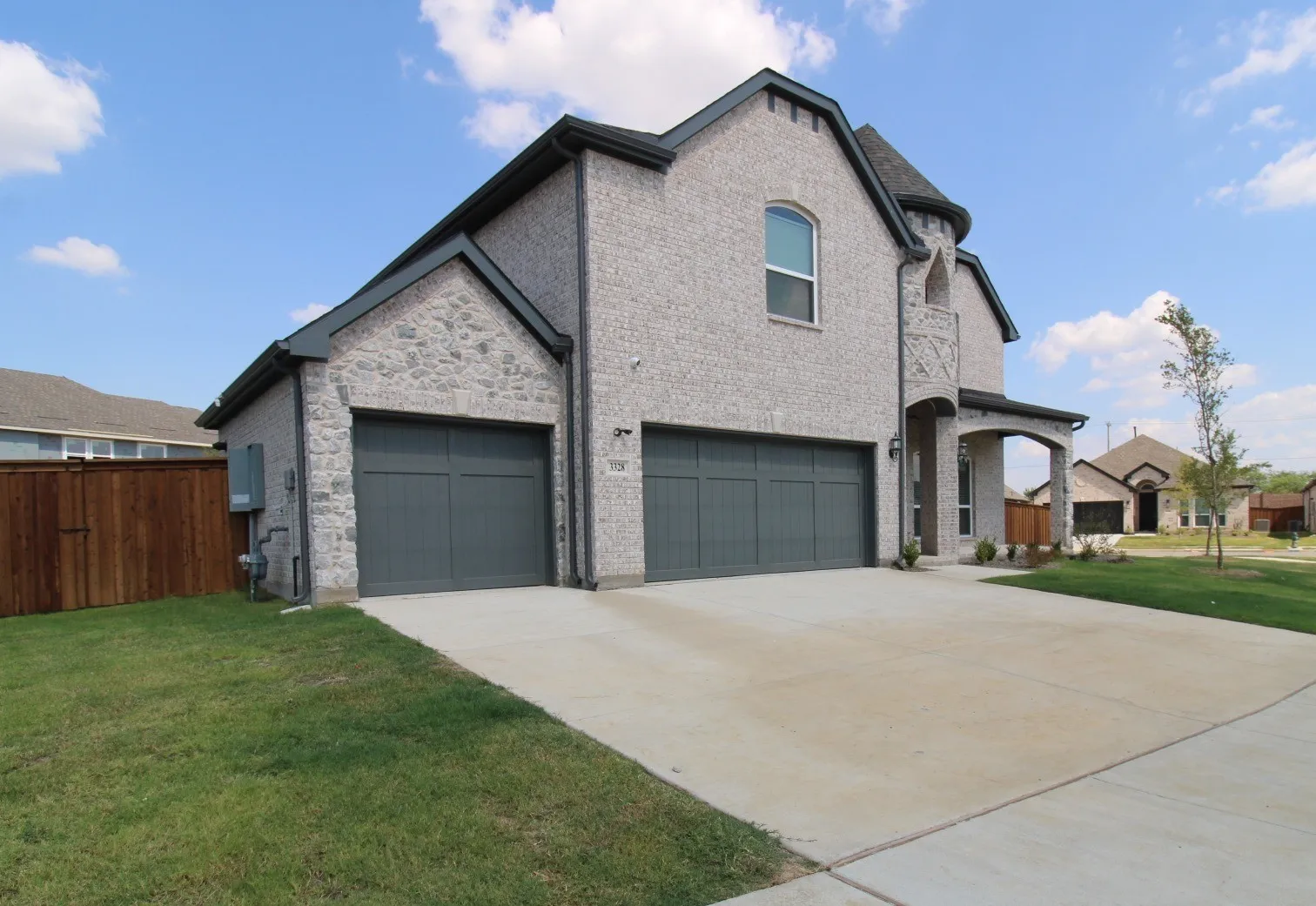 Stone façade with dark trim, dual garage doors, arched entry, and concrete driveway