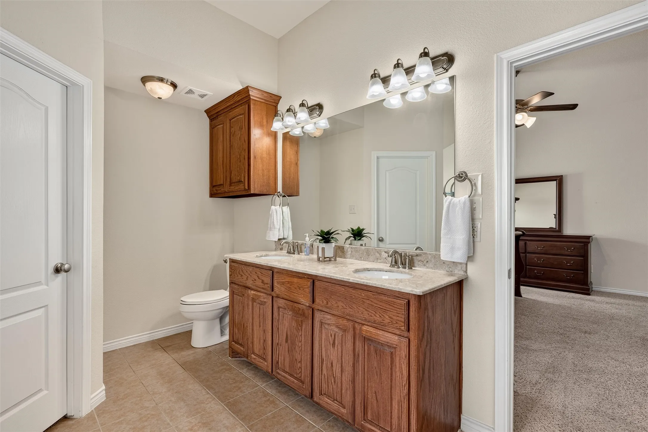 Double sinks and cabinet above the toilet