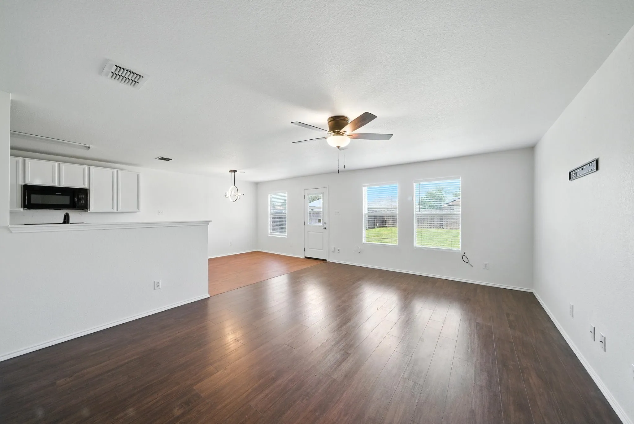 Unfurnished living room with ceiling fan and dark wood-type flooring