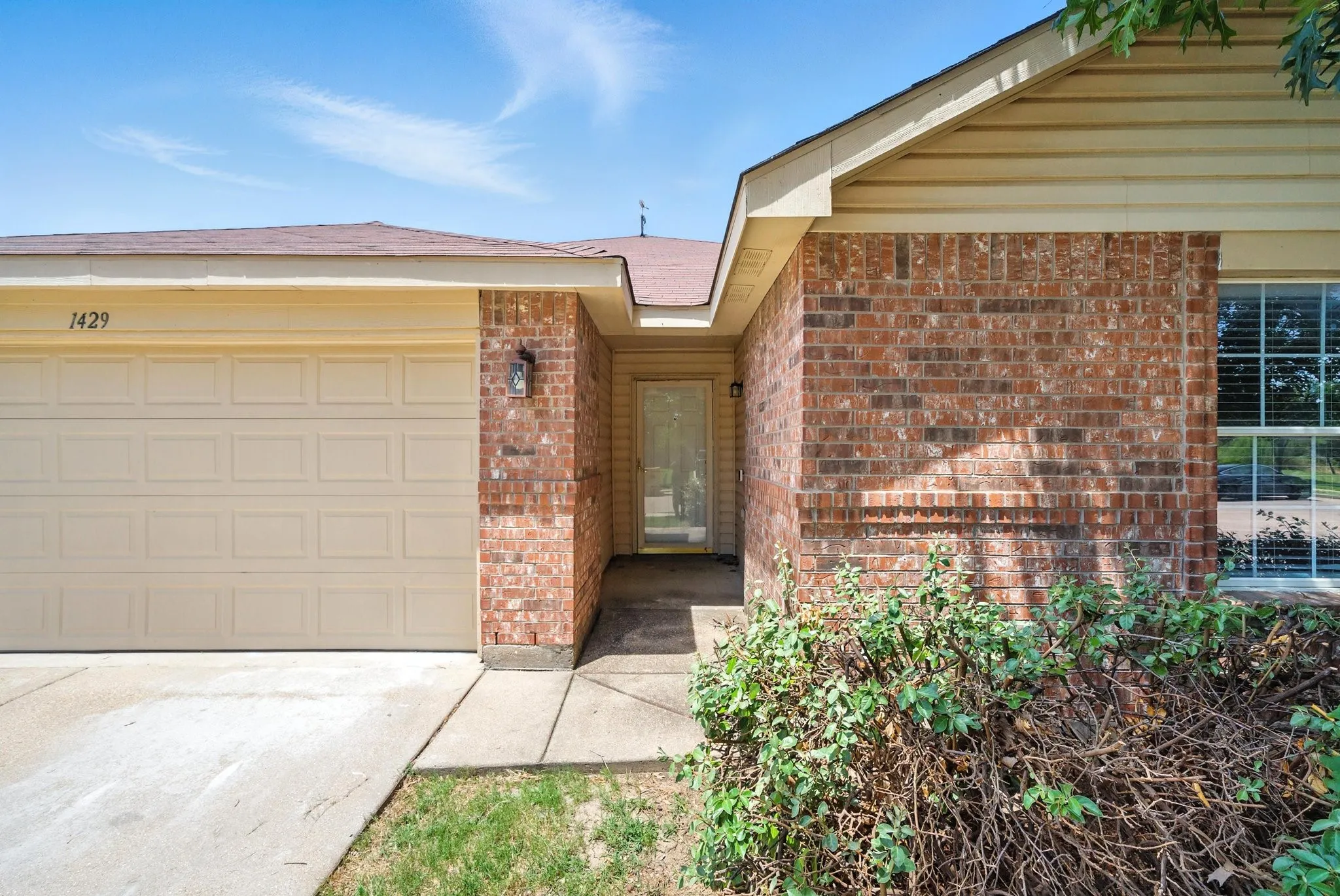 Property entrance with brick siding, concrete driveway, and a garage