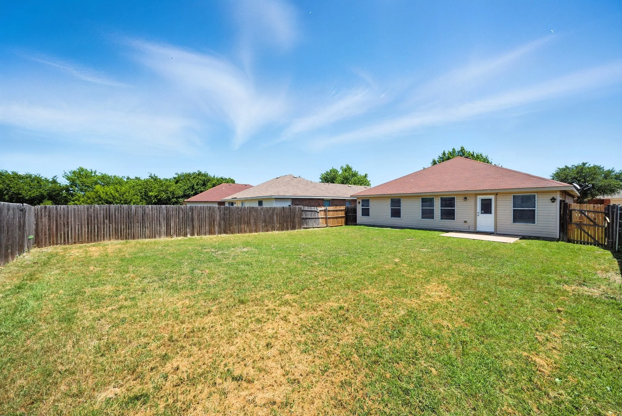 Rear view of property with a fenced backyard and a patio area