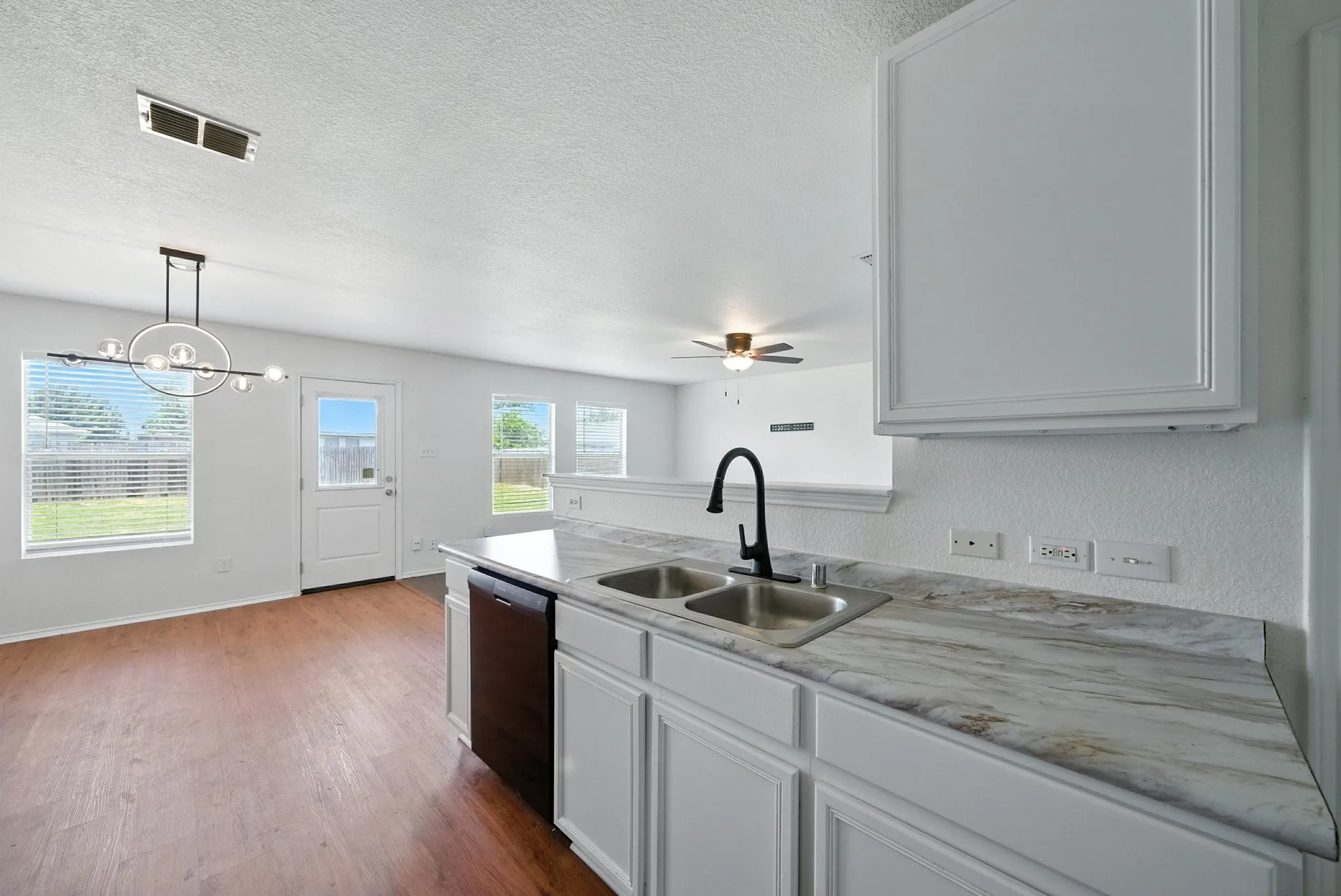 Kitchen with dishwashing machine, dark wood-style floors, a ceiling fan, light countertops, and a textured ceiling