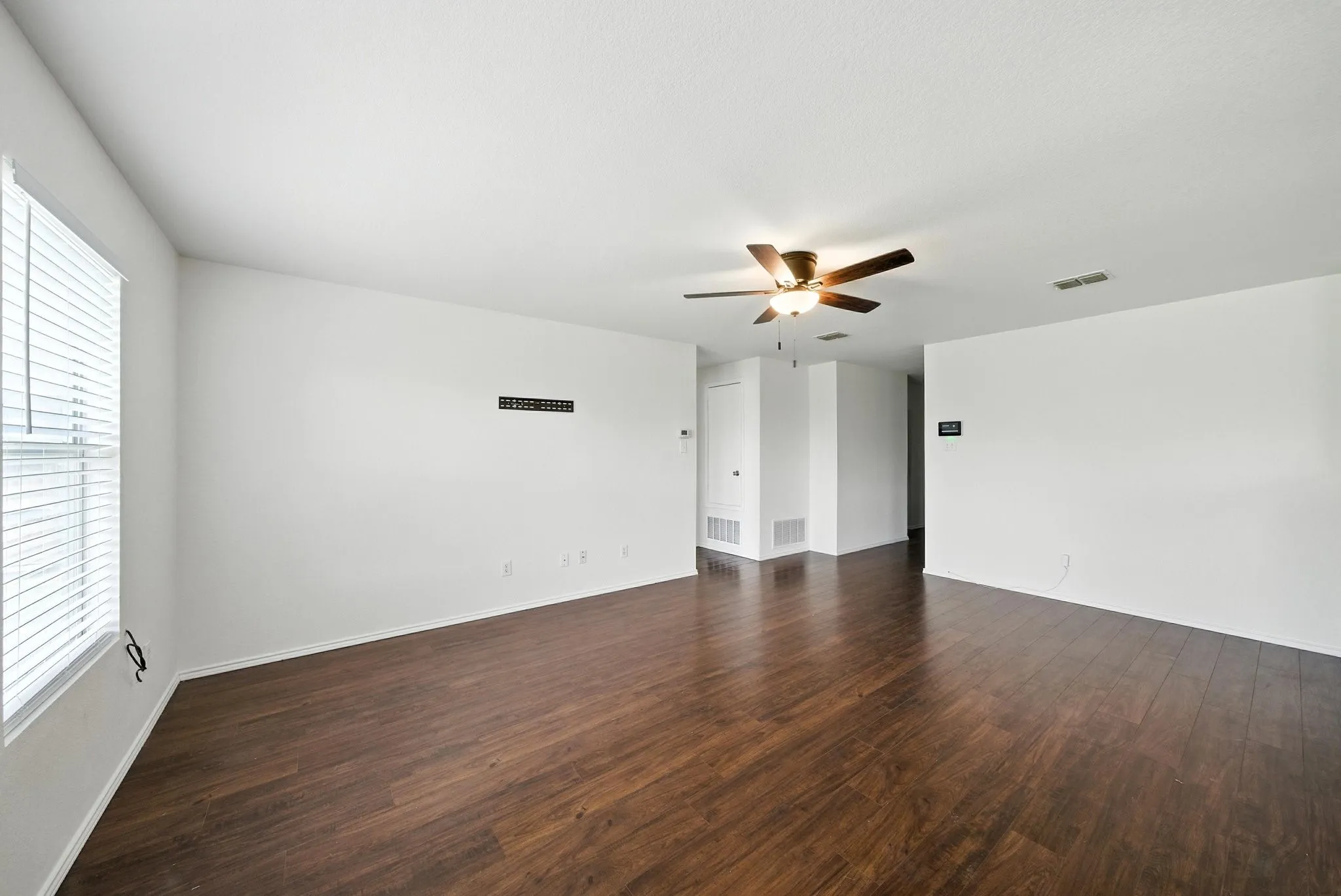 Empty room featuring a ceiling fan and dark wood-type flooring