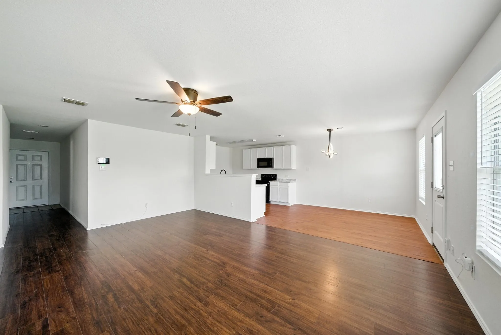 Unfurnished living room with a chandelier, dark wood-type flooring, and ceiling fan