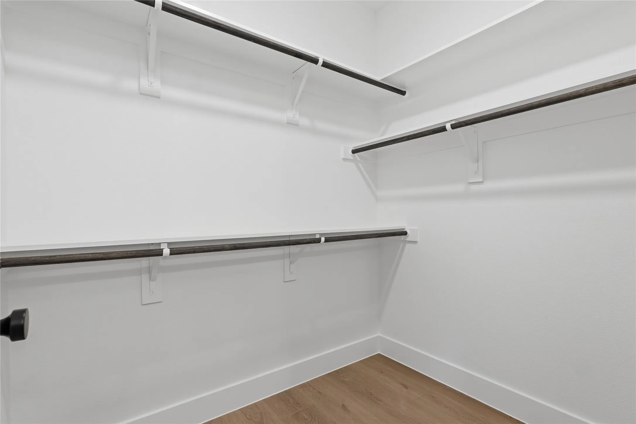 Walk-in closet featuring built-in shelving, hanging rods, and wood-finish​​‌​​​​‌​​‌‌​‌‌​​​‌‌​‌​‌​‌​​​‌​​ flooring
