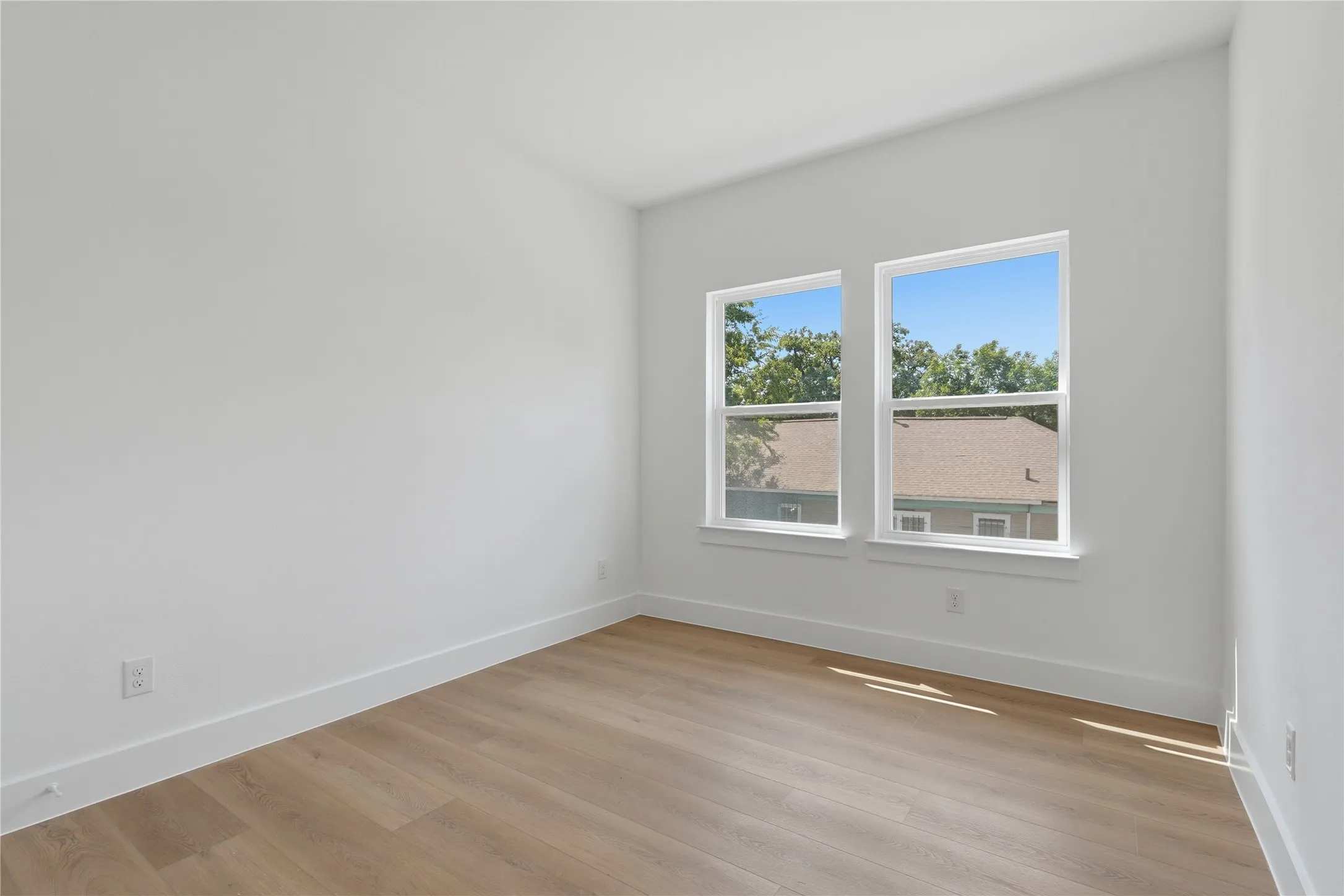 Wood-finish flooring, white walls, and two large windows with white trim