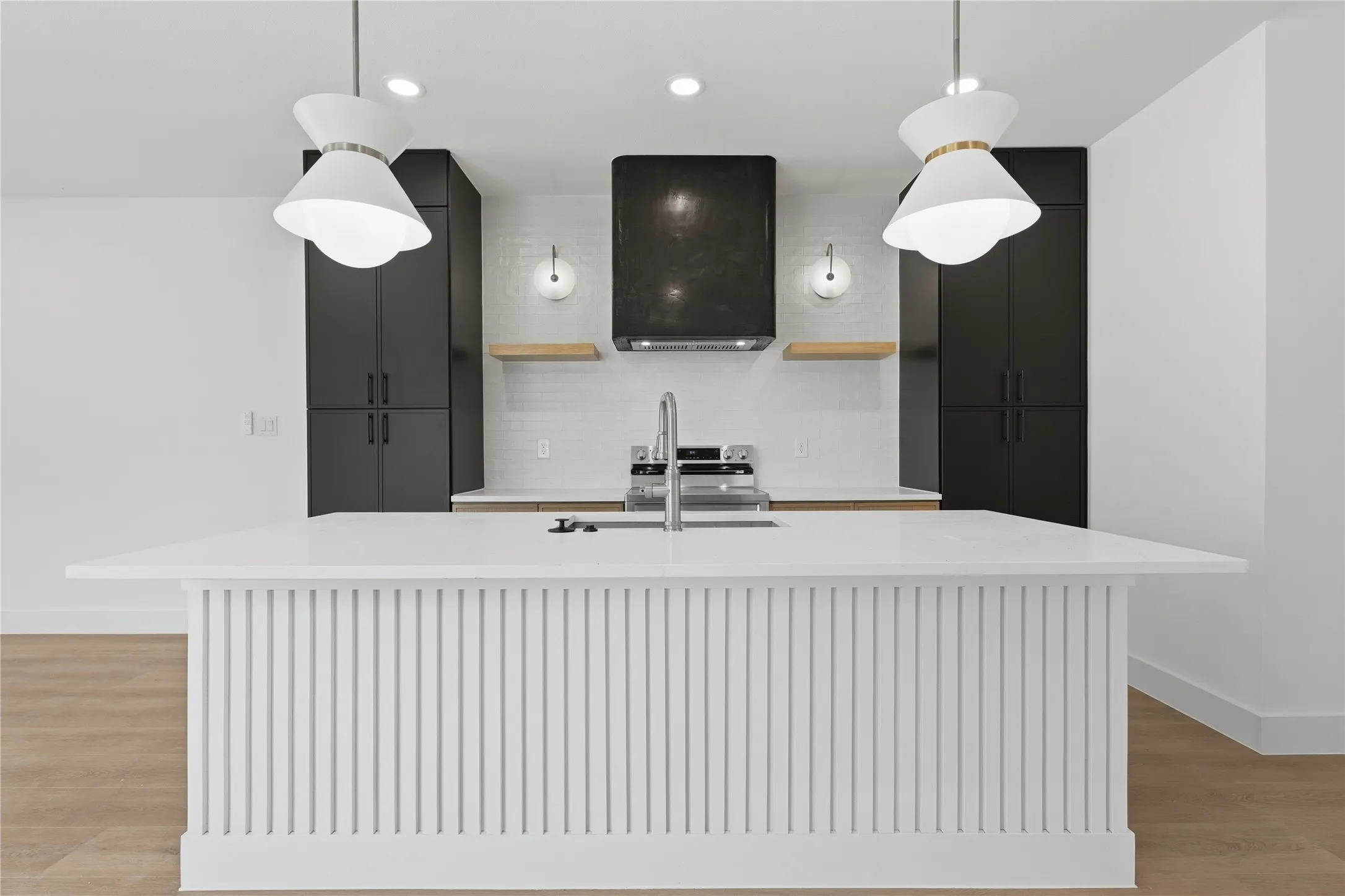 Kitchen island with vertical slat detailing and a solid surface countertop, equipped with a stainless steel faucet