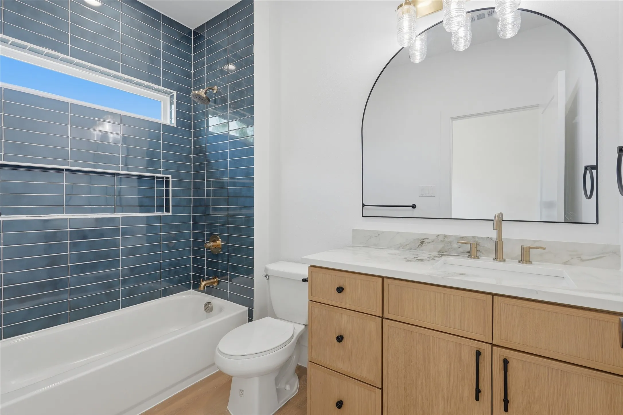 Contemporary bathroom featuring a wood-finish vanity with multiple drawers and brushed nickel hardware, white quartz countertop, and integrated sink