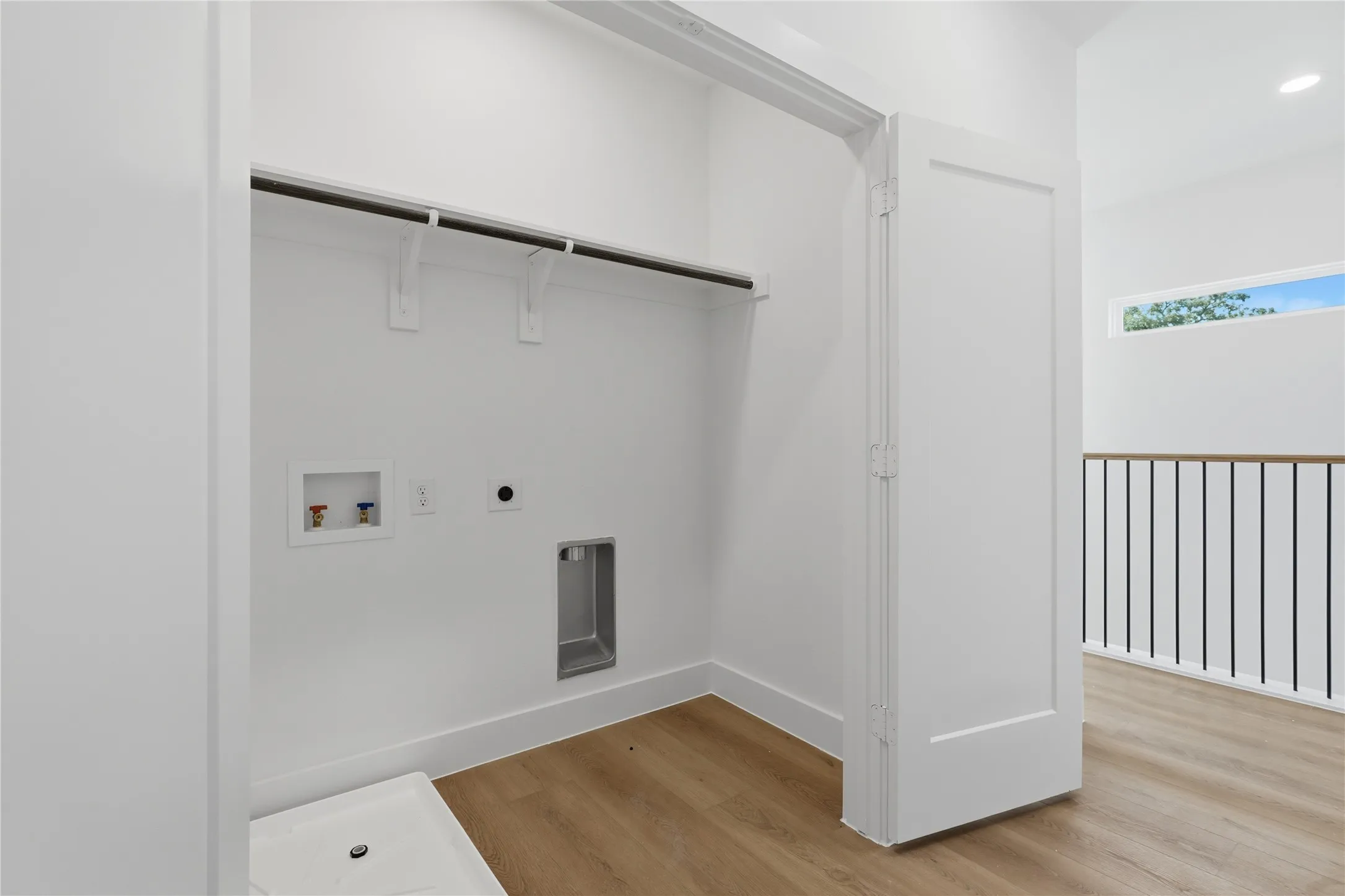 Laundry closet with hanging rod, water hookups, and a floor drain